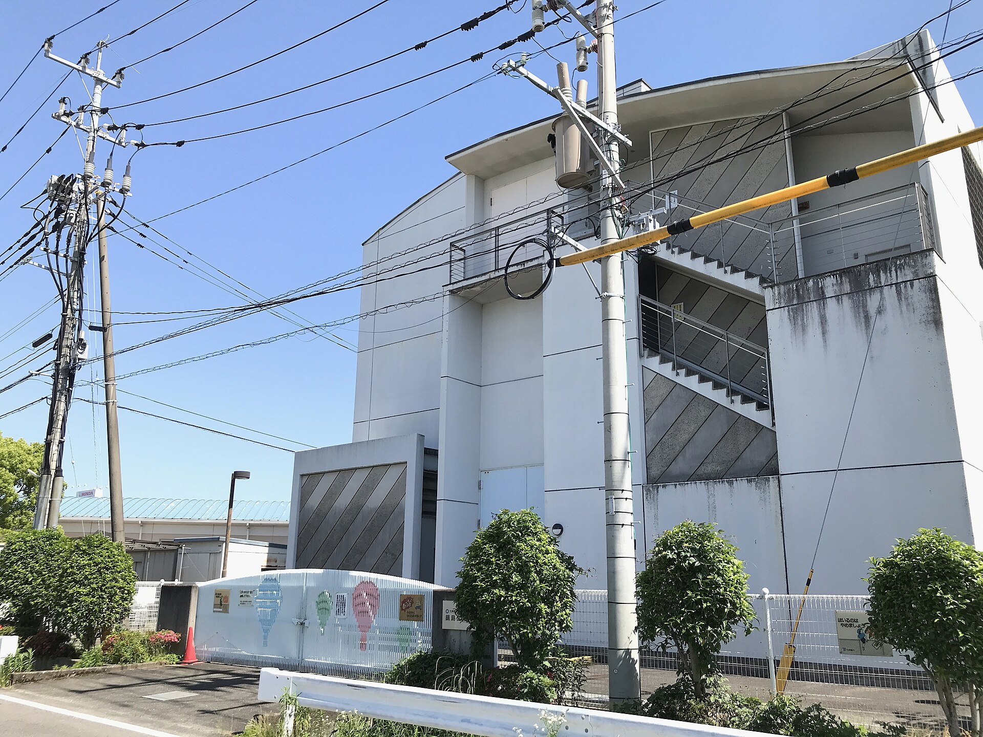 Building of Nabeshima Substation and vertical cables into distribution lines. A substation and lines belong to Kyushu Electric Power Transmission and Distribution Company. Utility poles hanger high-voltage and low-voltage distribution lines. Morita, Nabeshimamachi, Saga, Japan.