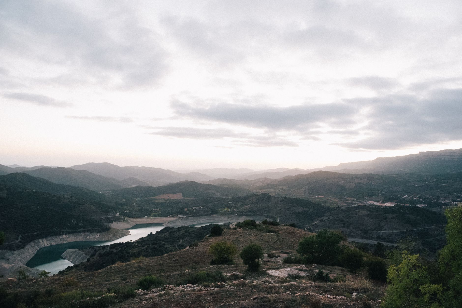 Stunning landscape of Siurana Reservoir in Spain with misty hills and cloudy skies.