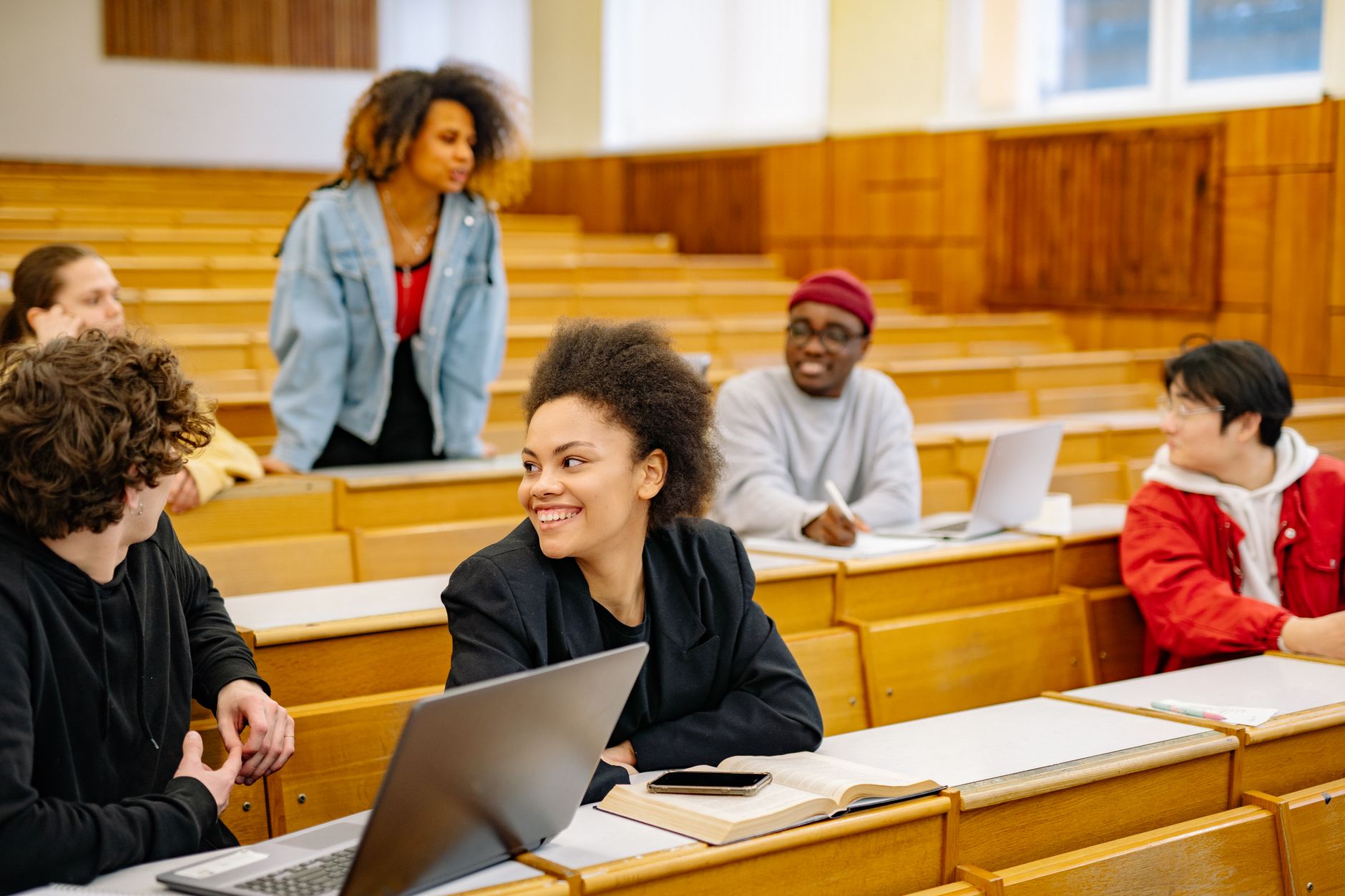 A diverse group of students engaging in discussion inside a college lecture hall.
