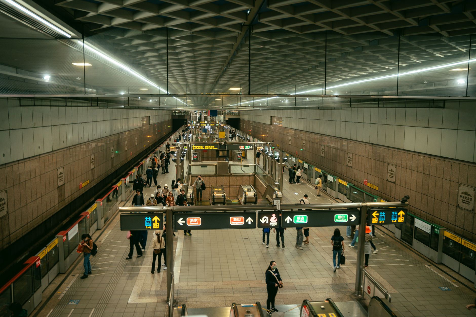 A busy Taipei Metro station with commuters navigating escalators and platforms during rush hour.