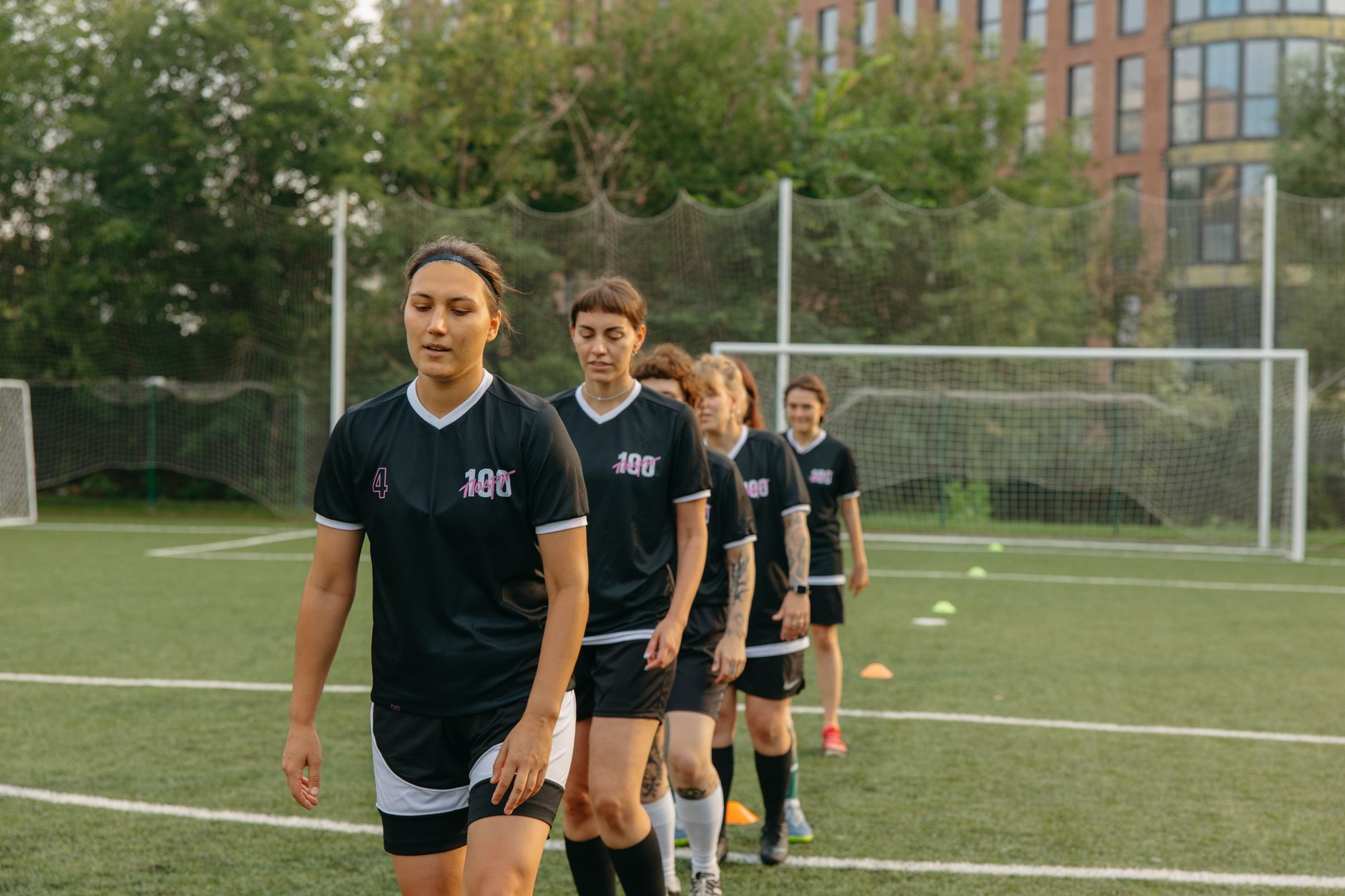 Women soccer players training on a green football field during the day.