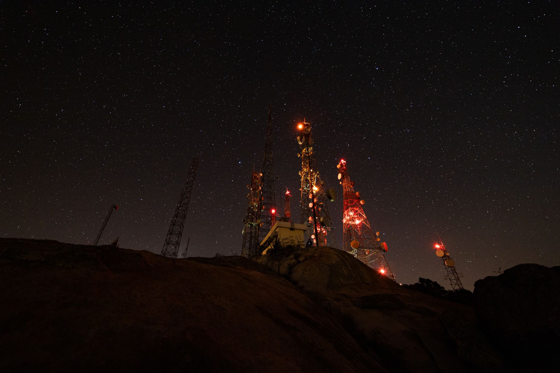 A mesmerizing night view of illuminated communication towers under a starry sky.