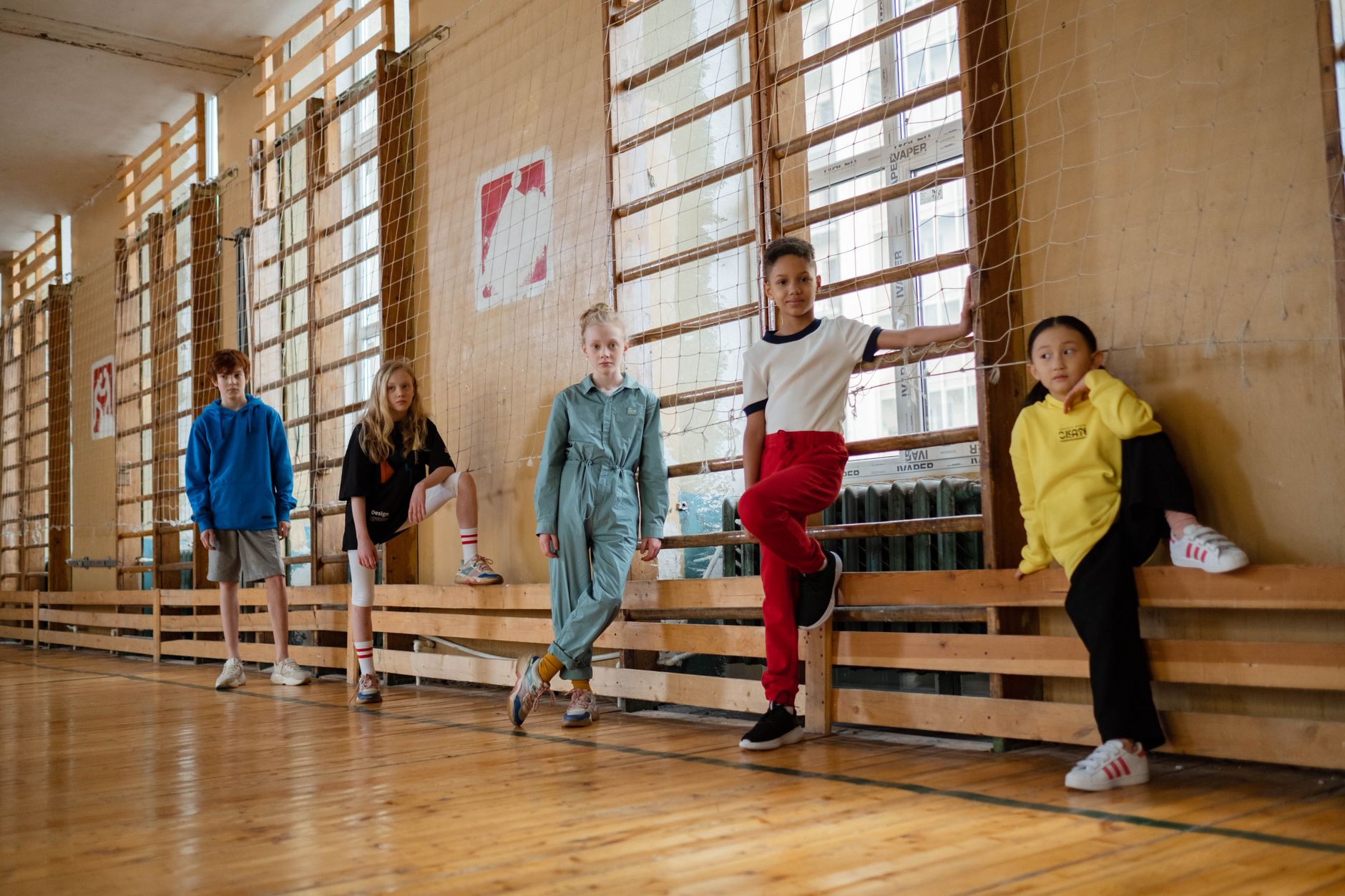 Group of diverse children posing indoors in a gymnasium setting, showcasing friendship and unity.