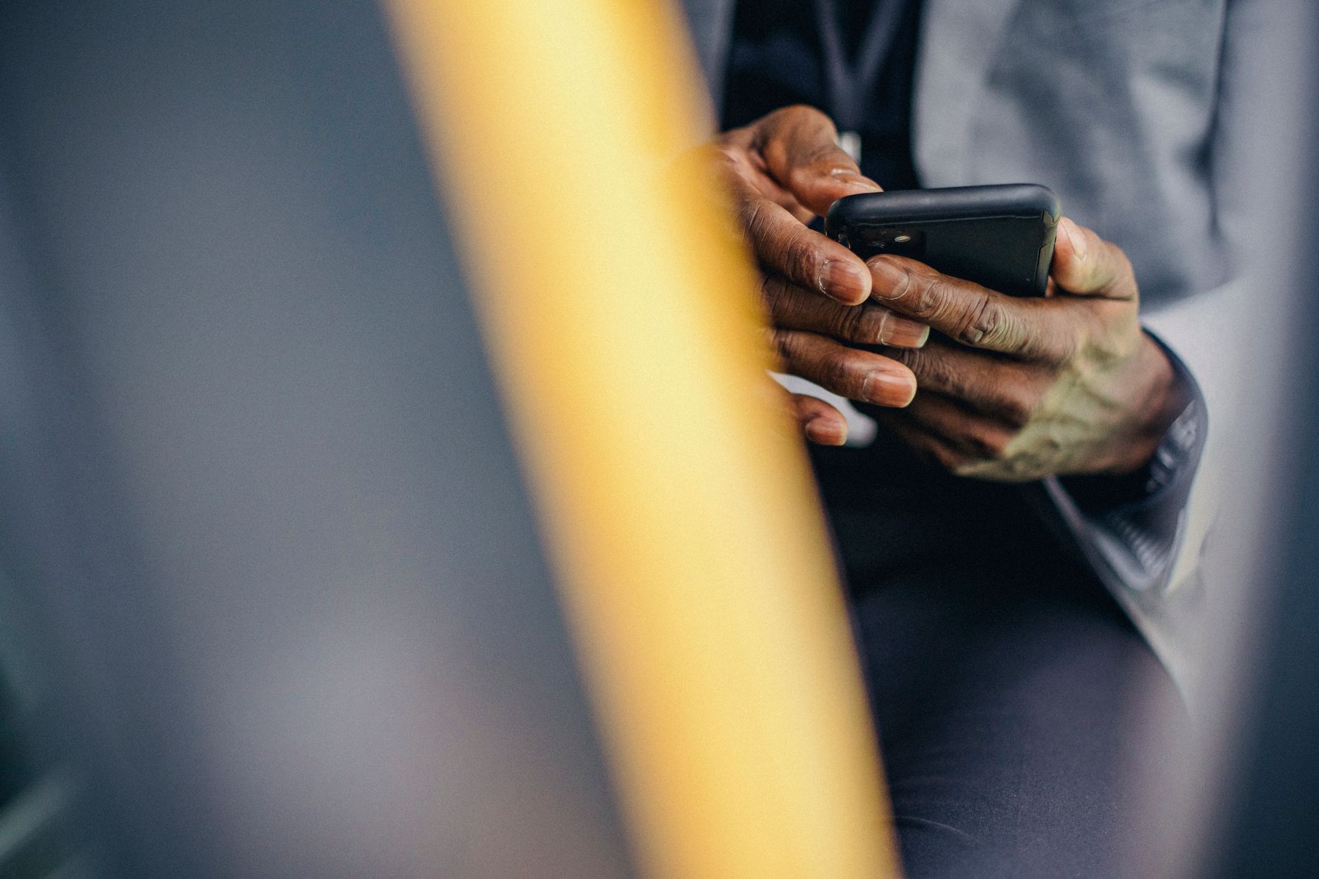 Crop anonymous male in formal clothes sitting in car and browsing modern mobile phone