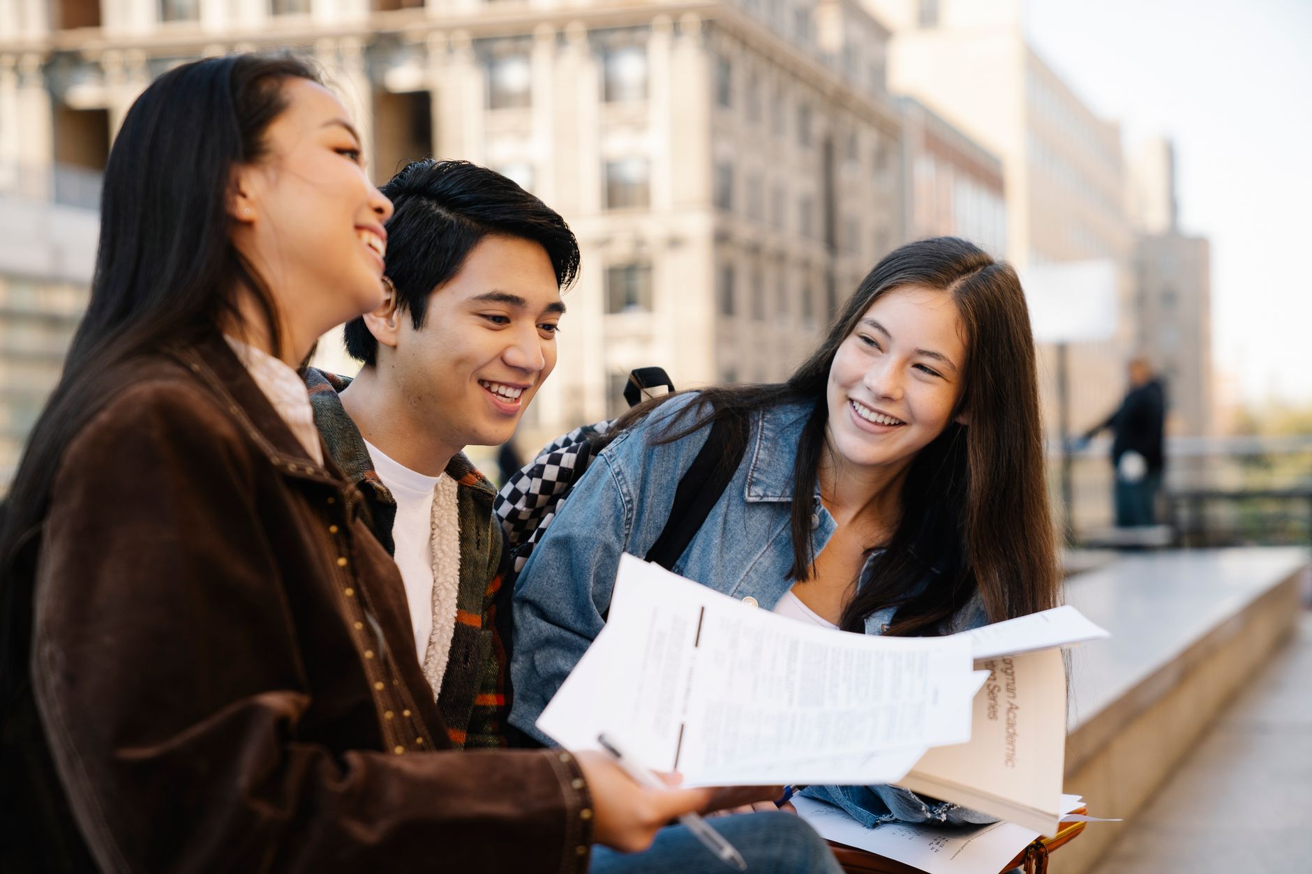 Three young adults sitting on campus benches, enjoying their conversation.