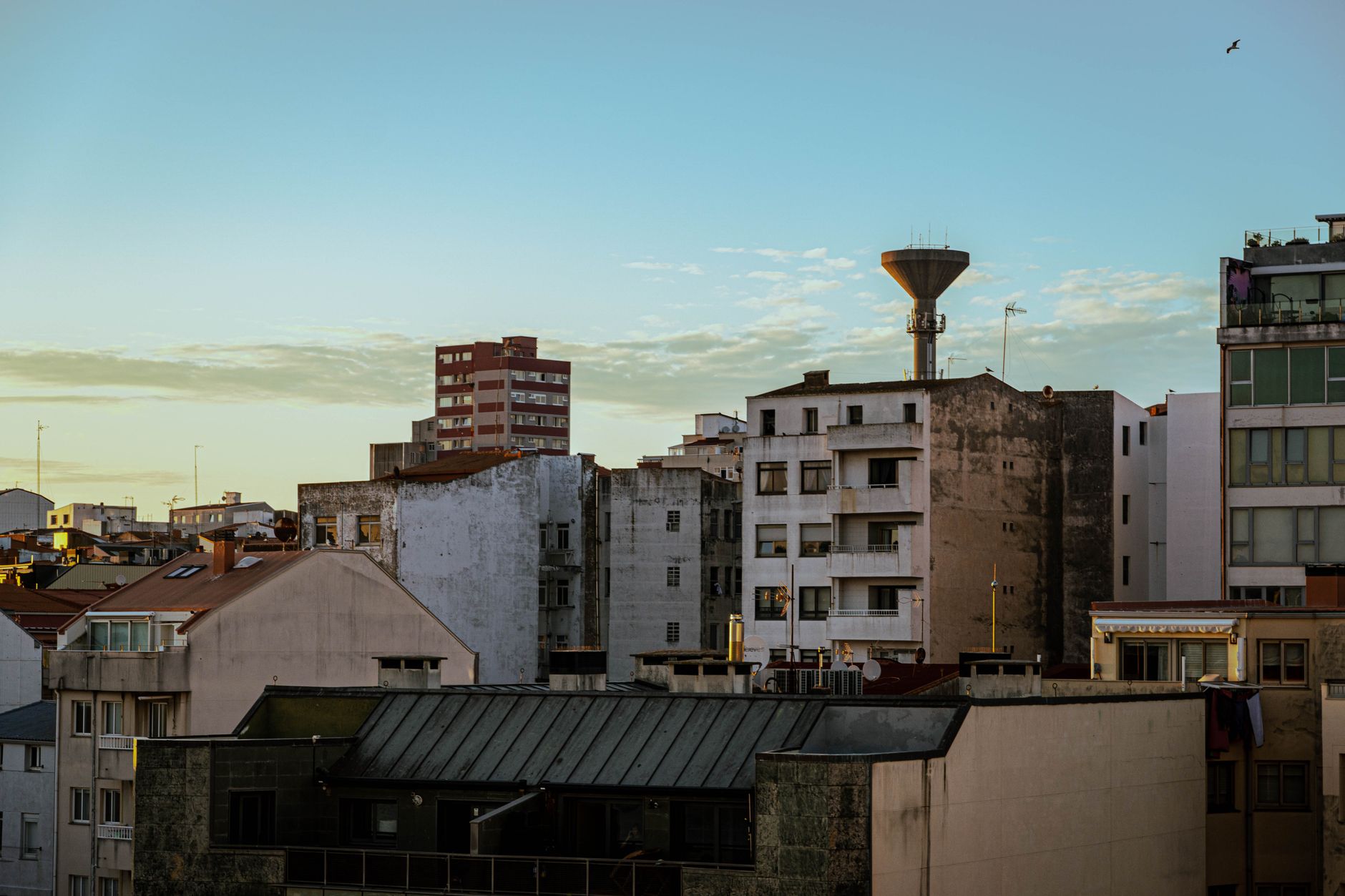 Scenic view of residential buildings at sunset in A Coruña, Spain with a water tower silhouette.