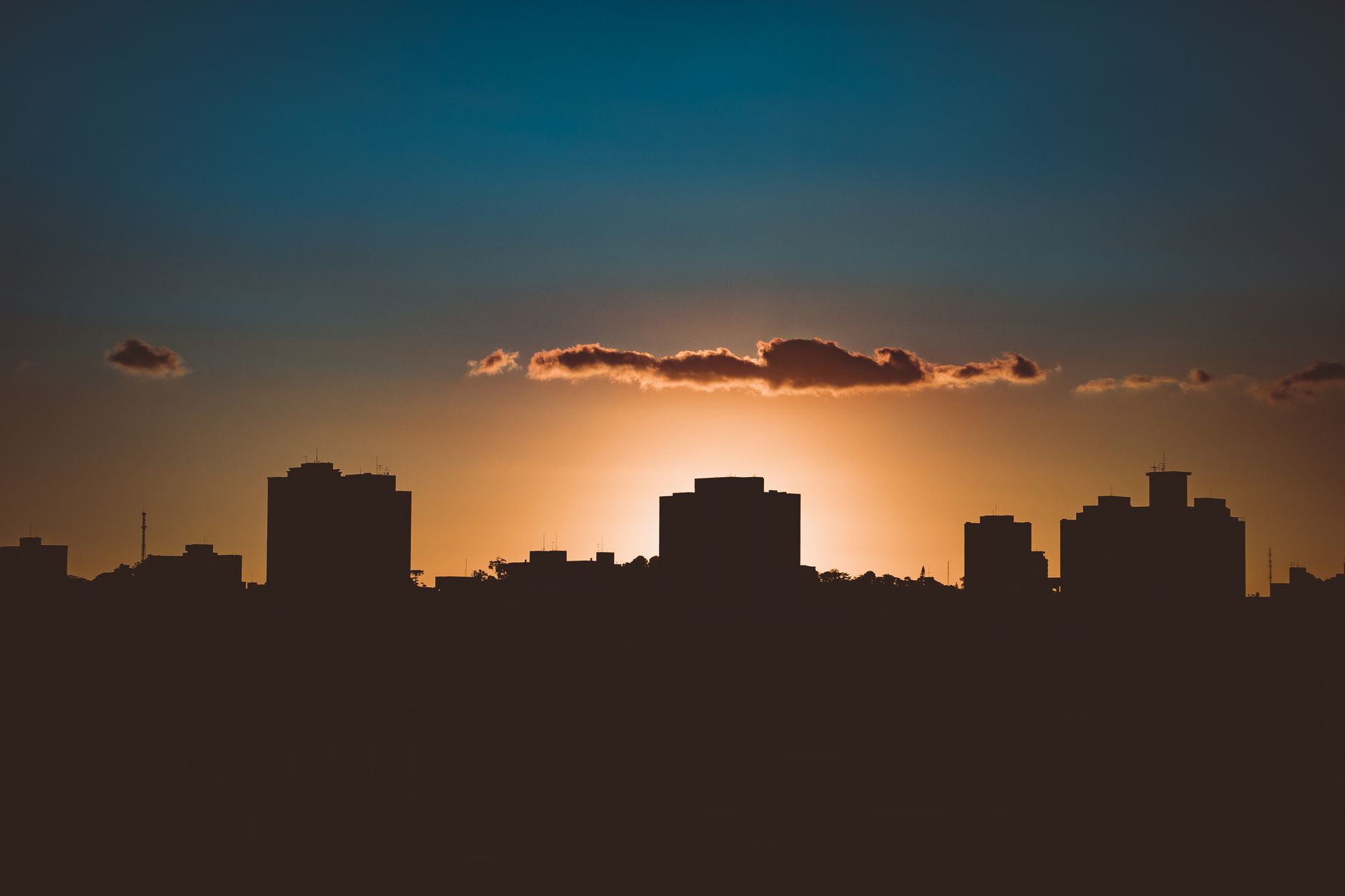 Dramatic city skyline silhouette with backlit sun during golden hour creating a stunning silhouette.
