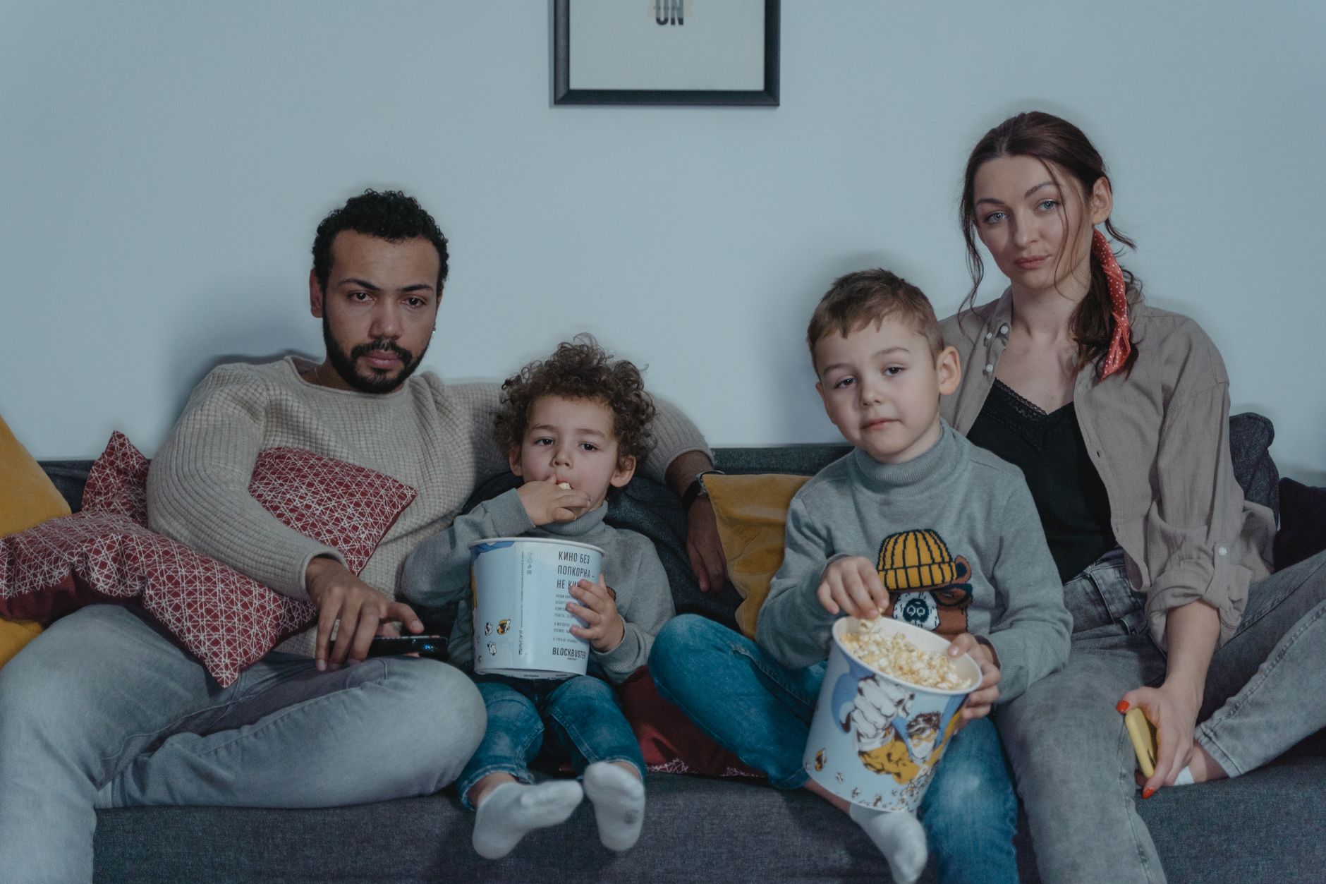 Family of four enjoying a cozy movie night with popcorn on the sofa.