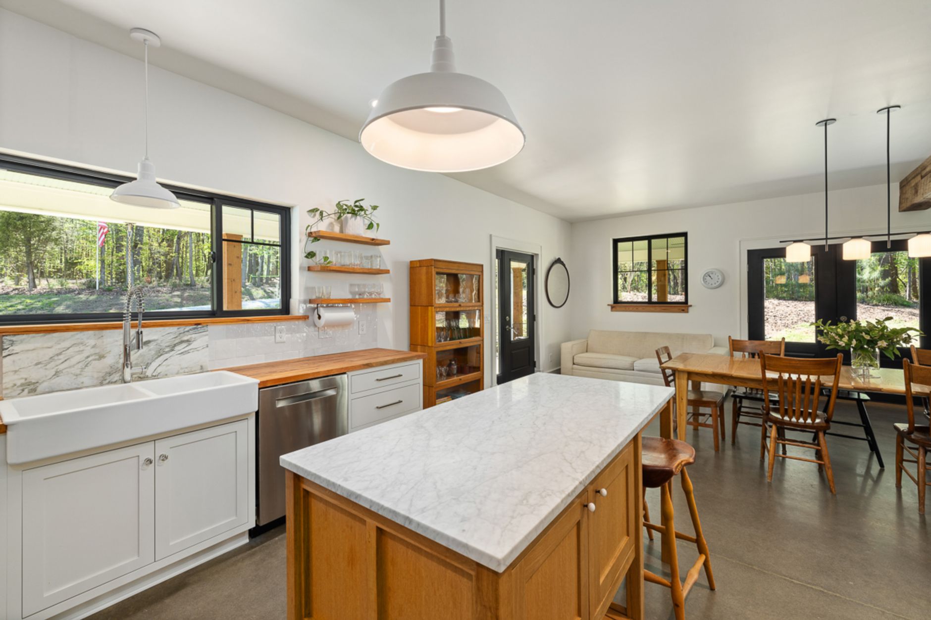 Bright modern kitchen with marble countertops, wood accents, and pendant lights.