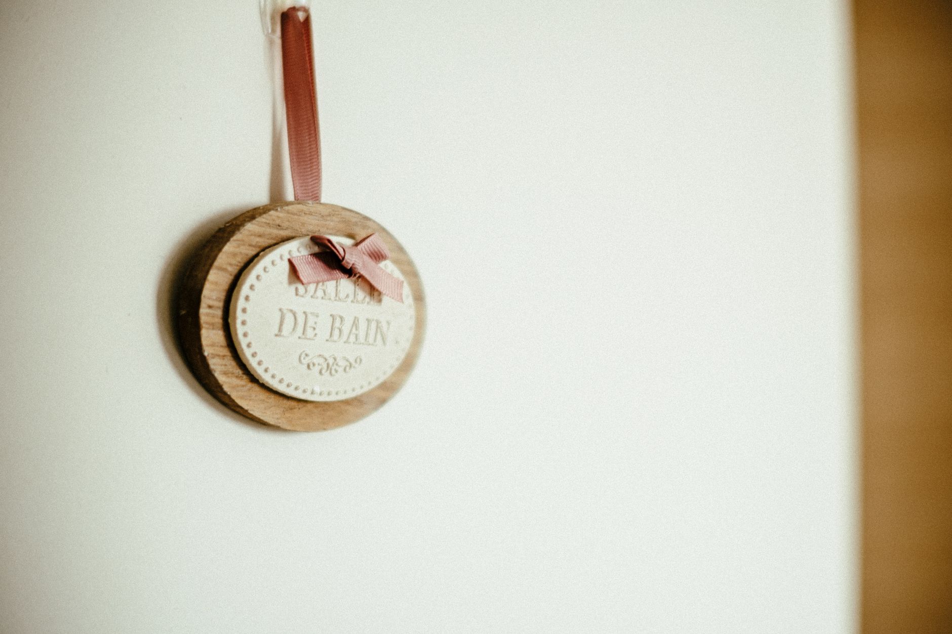 Elegant wooden wall plaque with 'Salle de Bain' text, featuring a pink ribbon, ideal for modern bathroom decor.