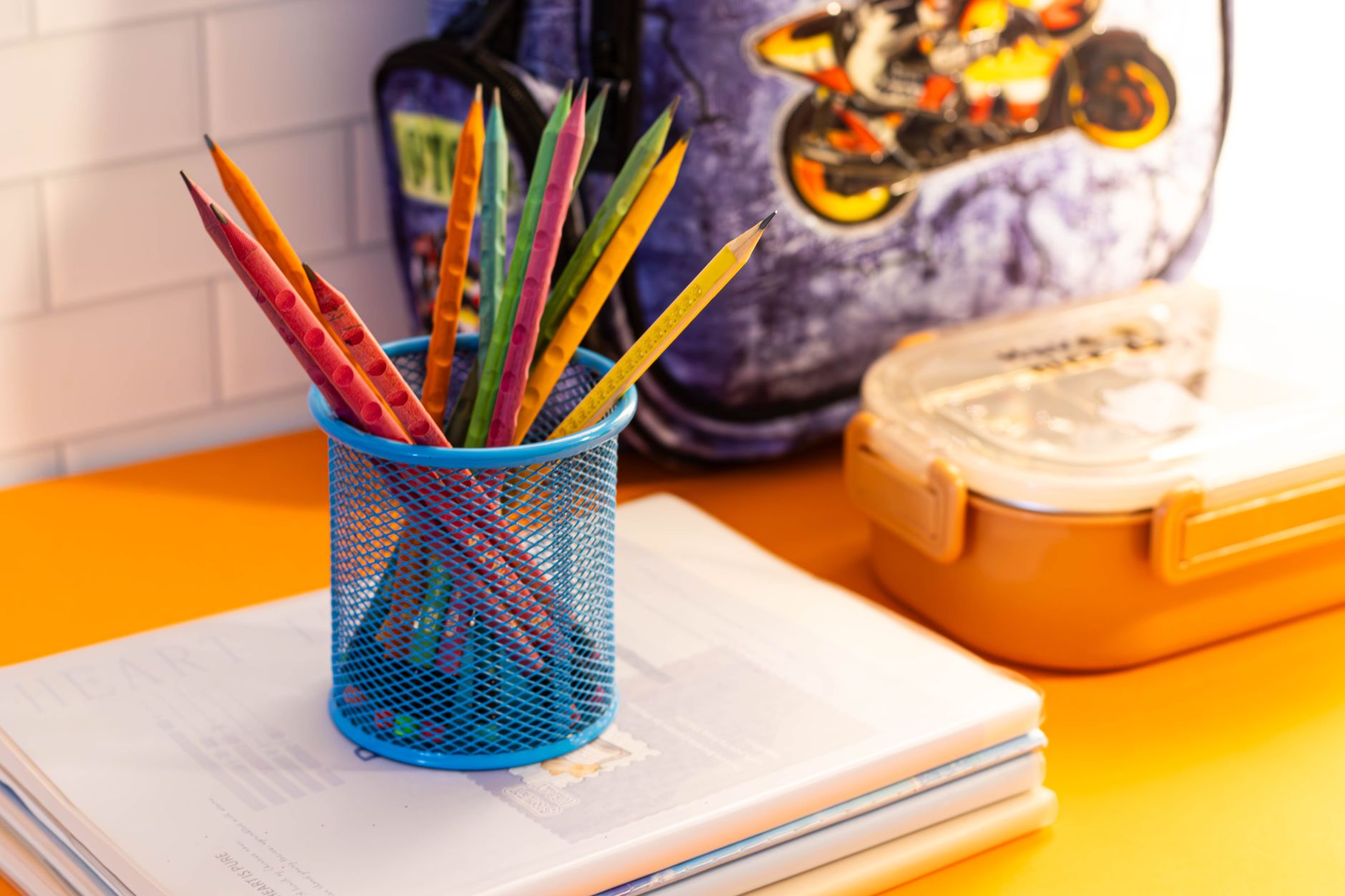 Vibrant school supplies including pencils, notebooks, and backpack on a classroom desk.