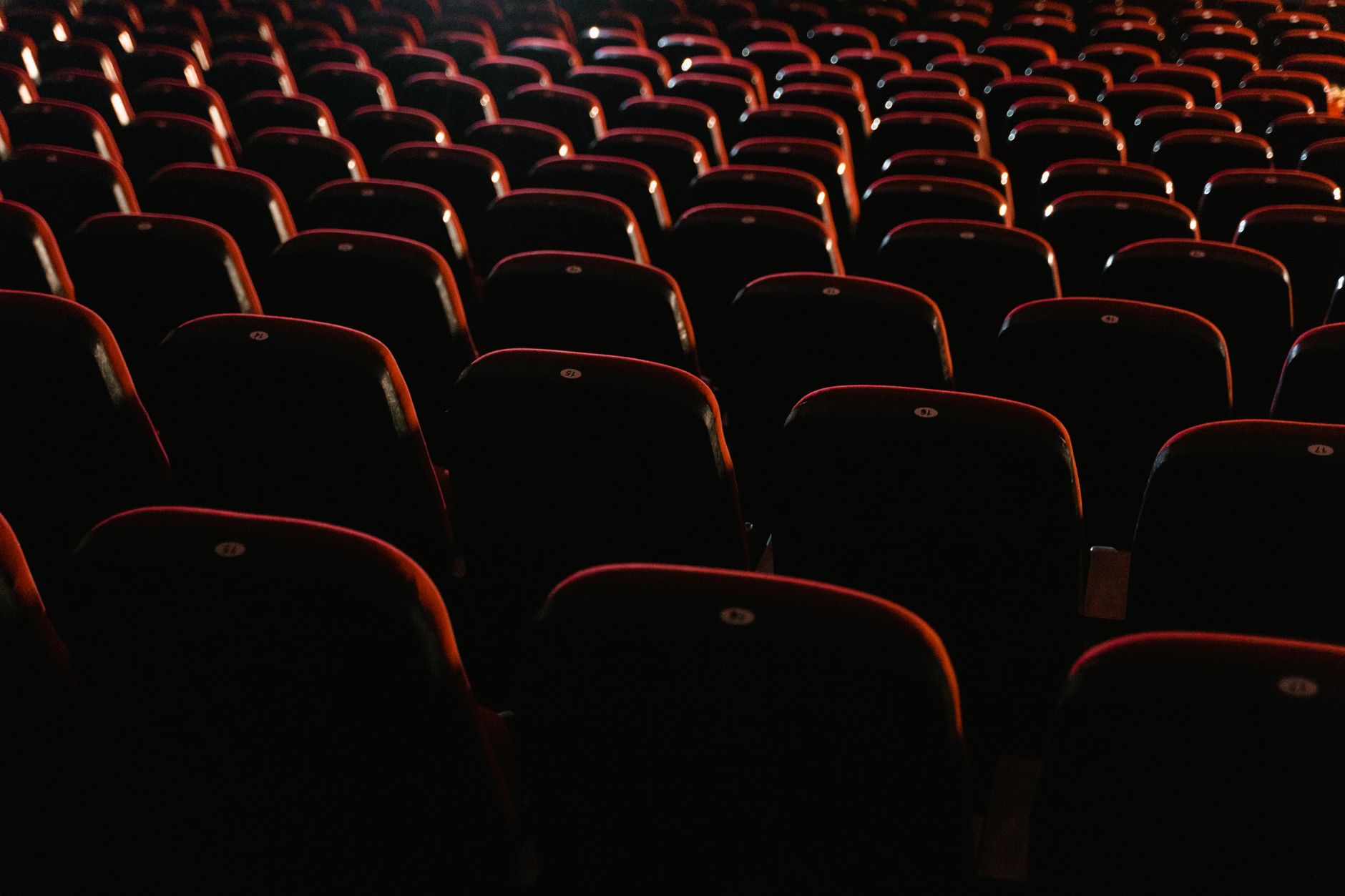 Rows of empty red seats in a dimly lit movie theater, showcasing a cinema environment.