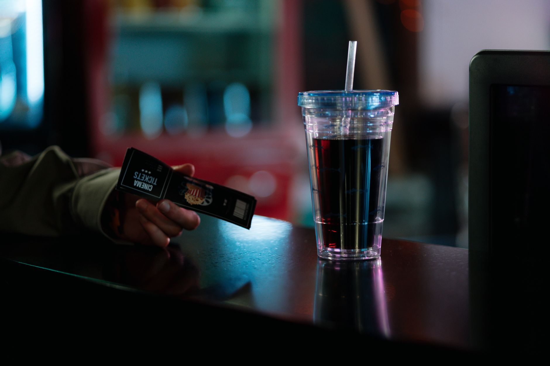 Close-up of cinema tickets and a soda cup on a counter. Ideal for entertainment themes.