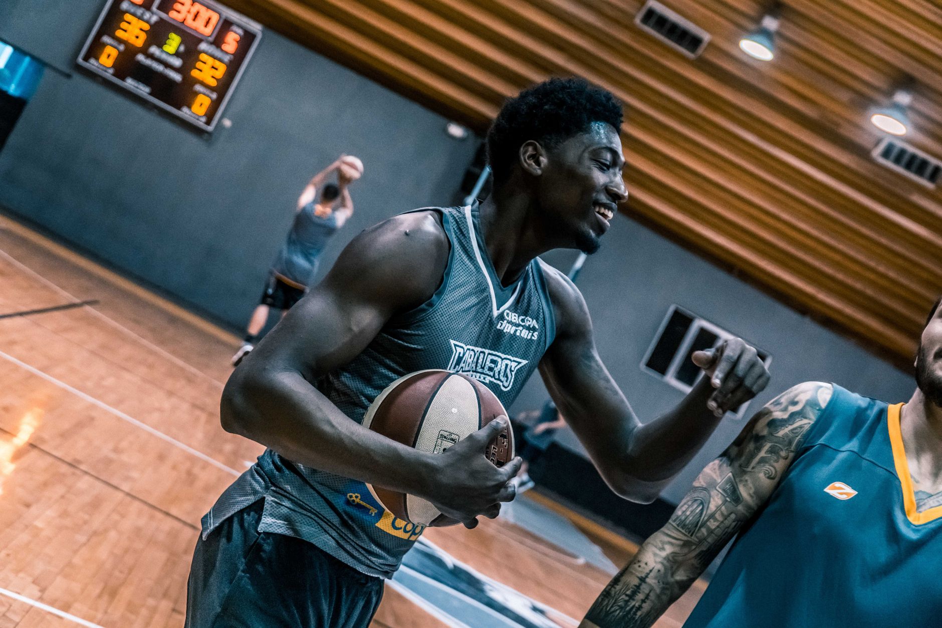 Engaging moment of basketball players during an indoor training session on a wooden court.
