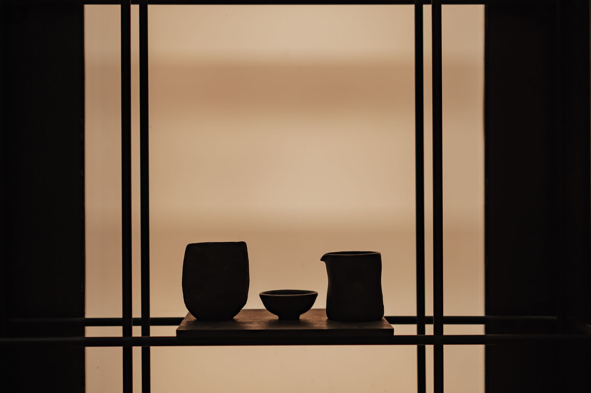 Minimalist display of ceramic vases on a wooden shelf against a soft background, showcasing elegant interior decor.