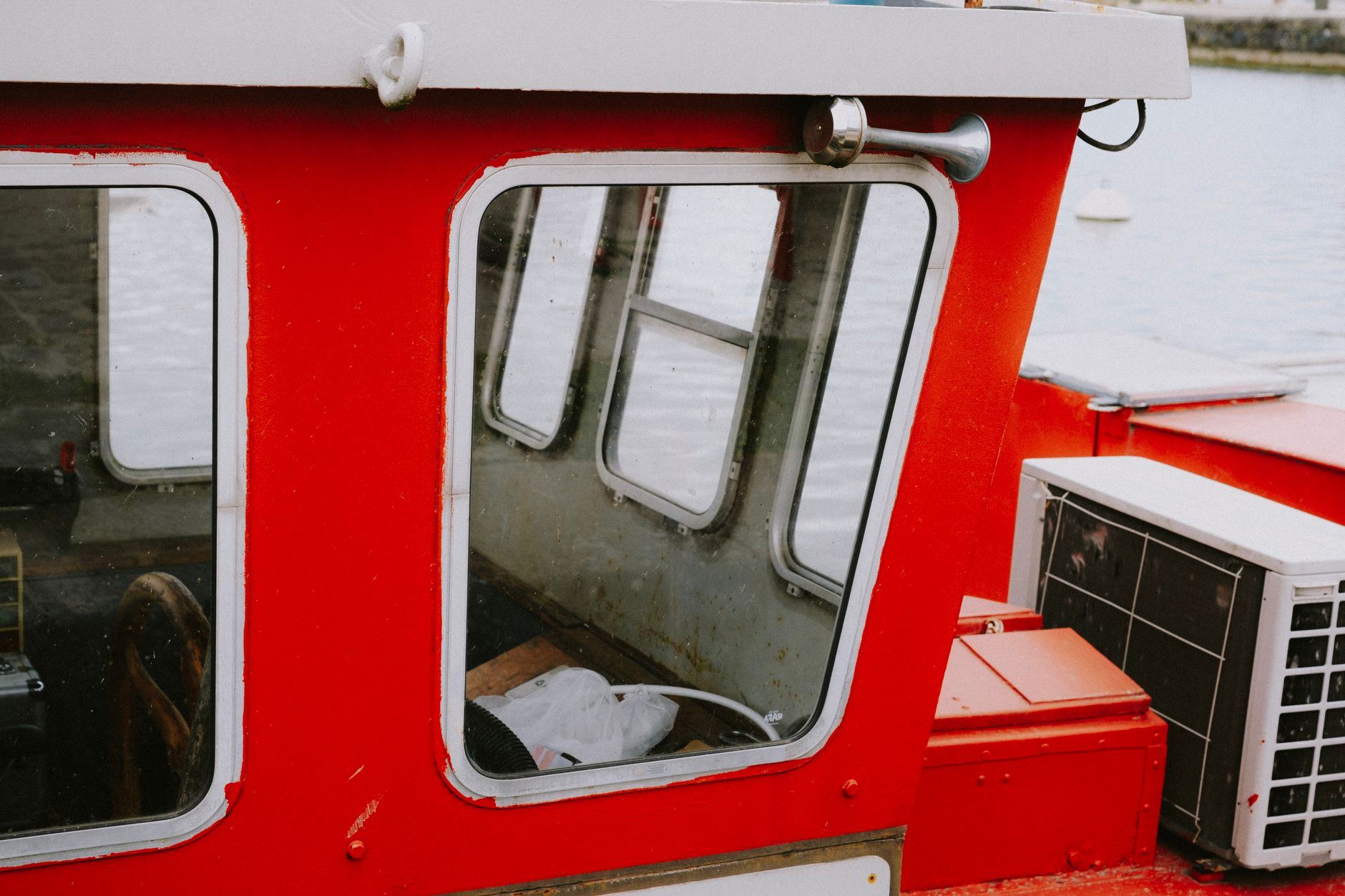Detailed image of a red boat cabin showing windows and equipment by the water.