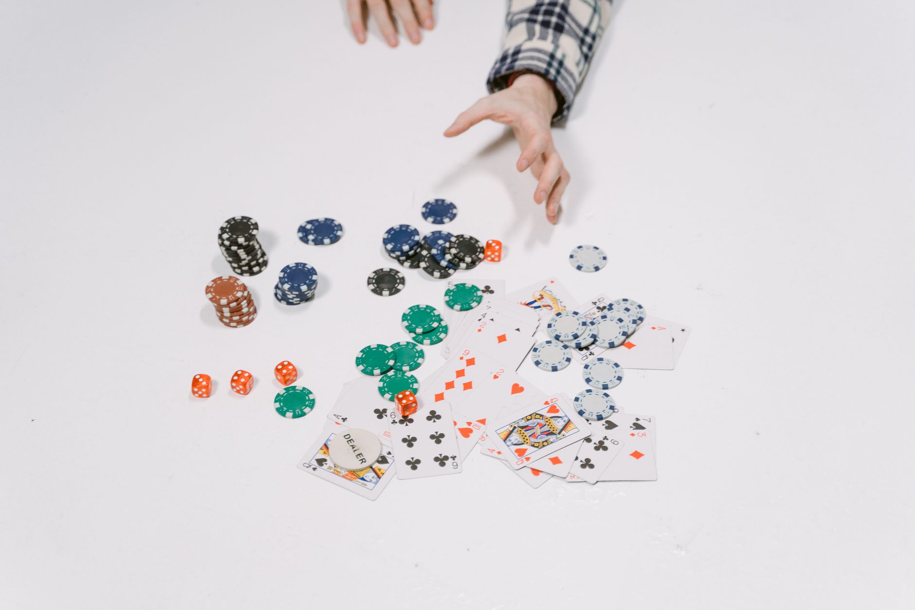 Close-up of poker chips and cards on a white surface, capturing a moment in a card game.