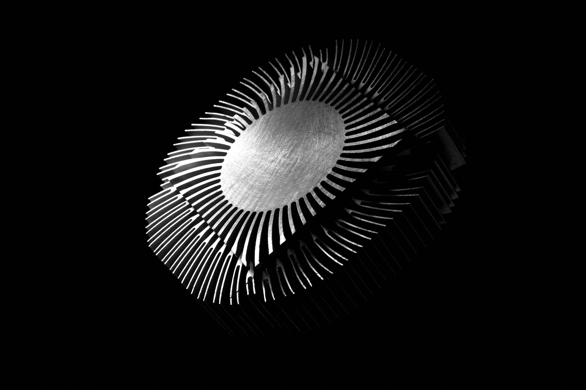 Close-up abstract image of a metallic heat sink with intricate patterns on a black background.