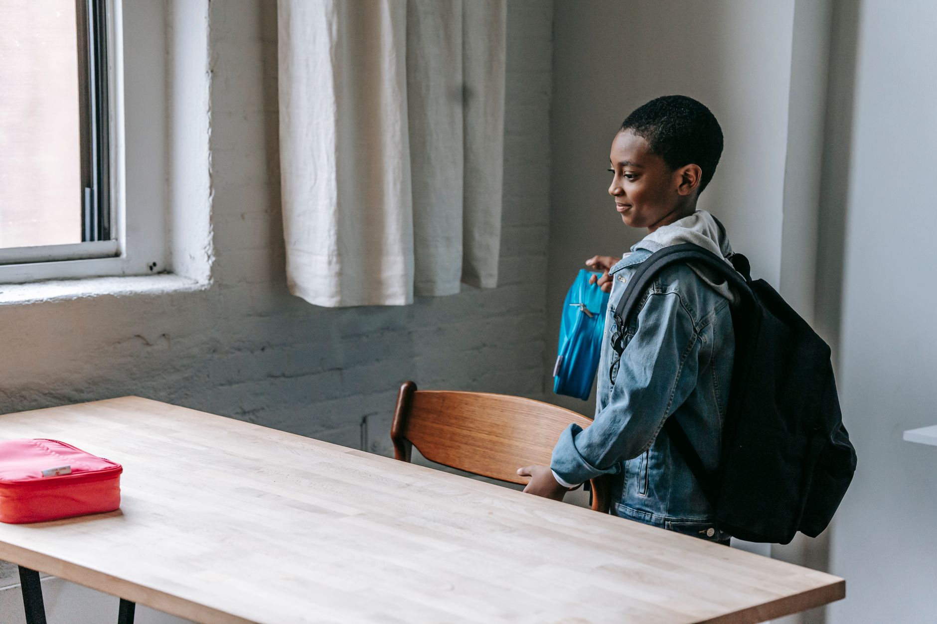 Side view of cute African American child holding lunch box while preparing for snack in school