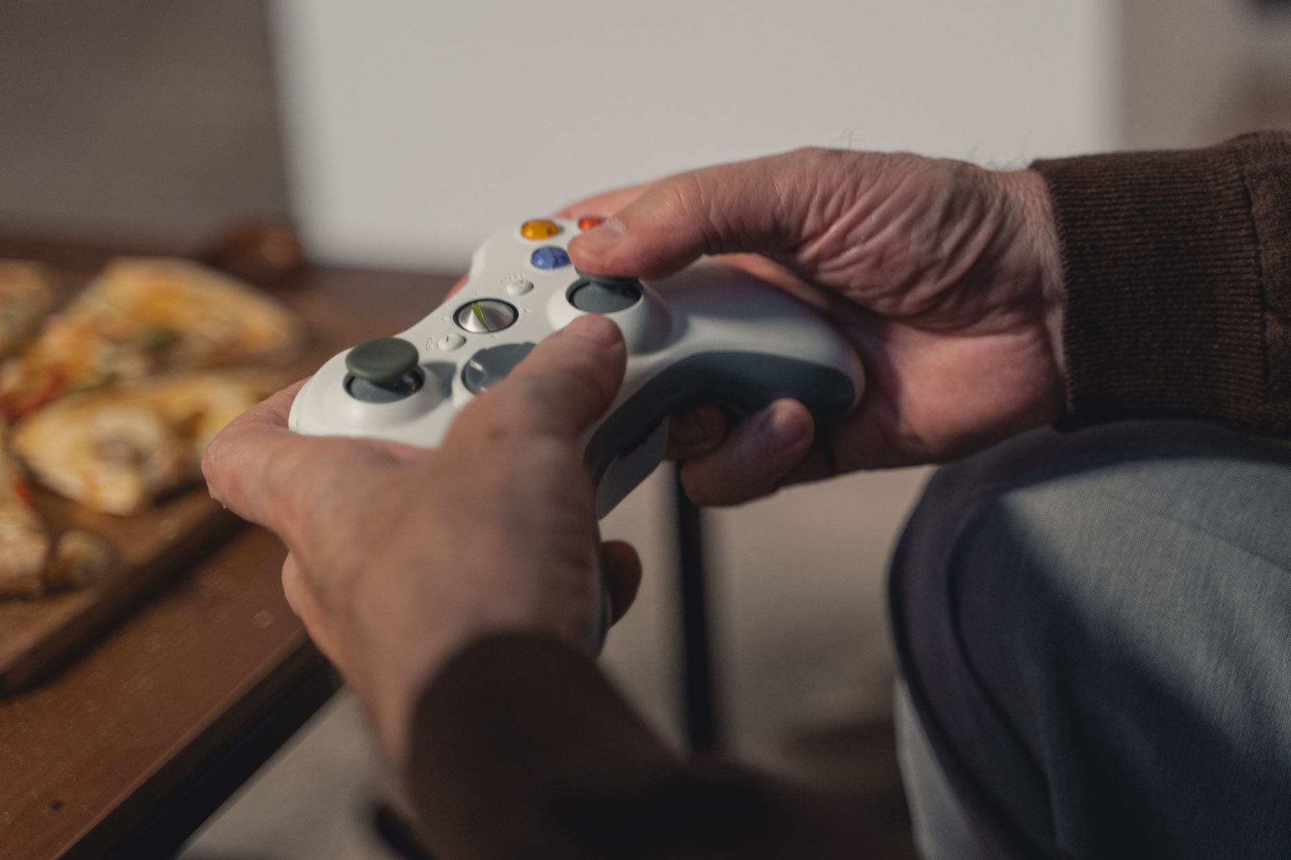 A senior adult holding a game controller, enjoying a leisurely moment indoors.