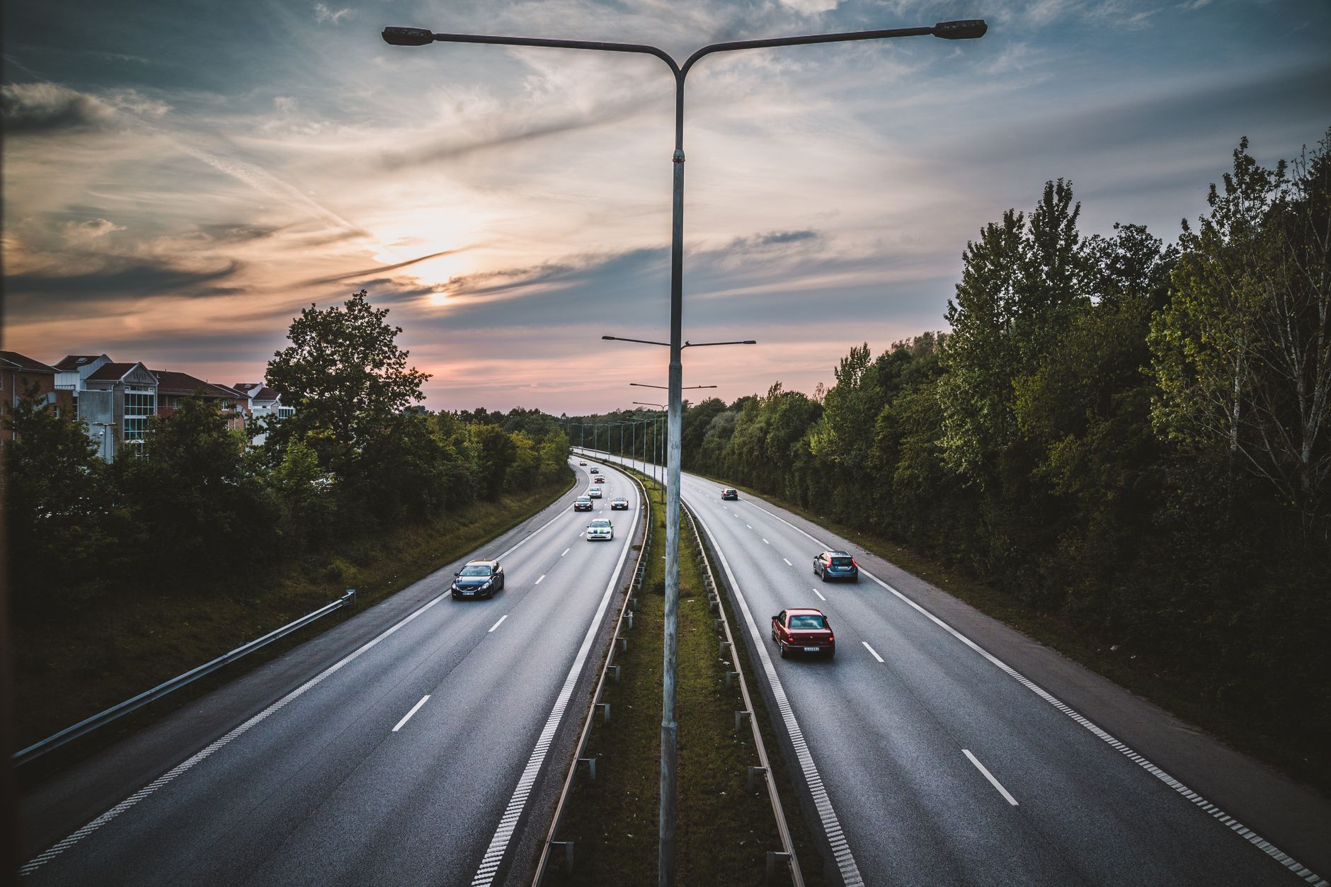 Aerial view of a highway in Lund, Sweden, featuring cars and a dramatic sunset sky.