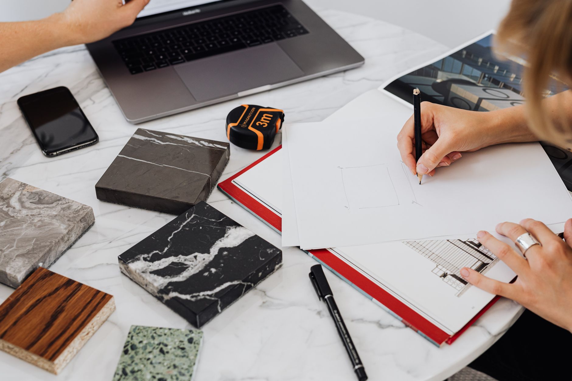 Workspace showing architectural design process with material samples and drawing.