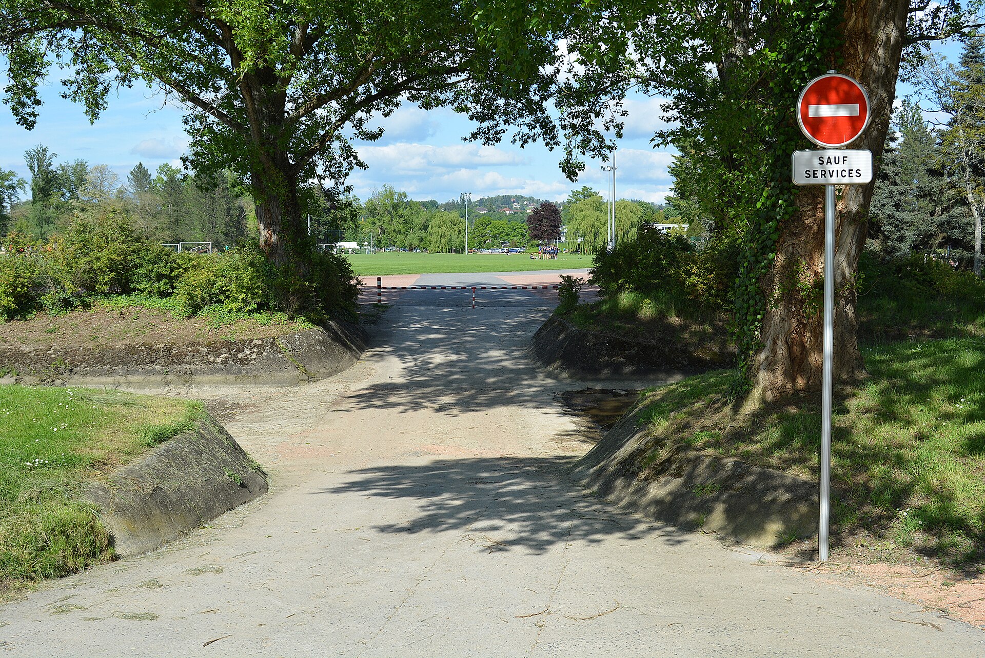 Passage à gué de la rivière artificielle du parc omnisports Pierre-Coulon, à Bellerive-sur-Allier (Allier, Auvergne-Rhône-Alpes, France), entre le parking P7 (desservant le boulodrome) et le chemin longeant les terrains 4 à 8. Son accès est interdit à tout véhicule sauf aux services, même si un passage à pied ou à vélo est possible ; ici, la rivière est asséchée.