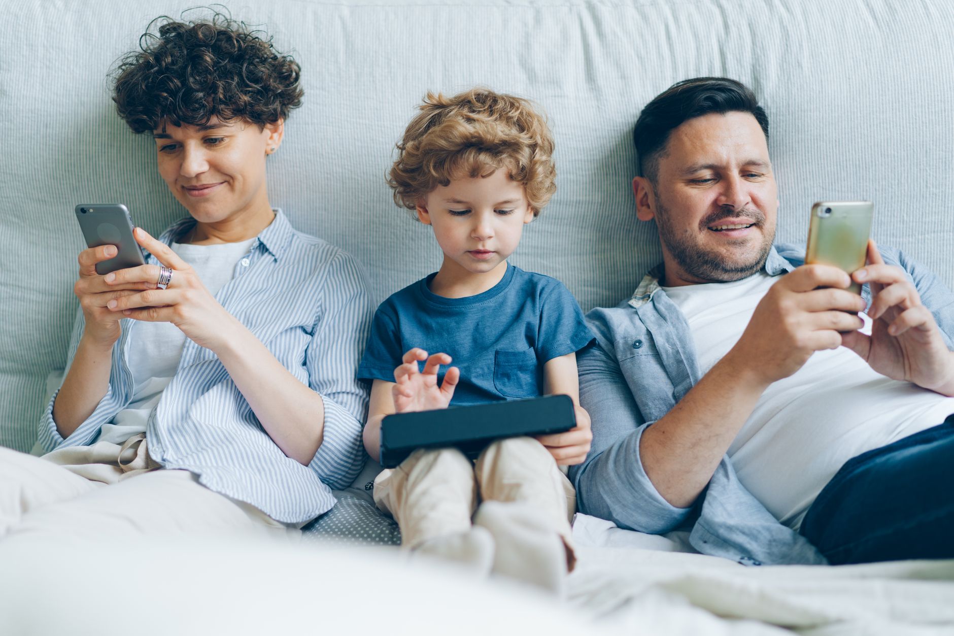 Happy family enjoying screen time together on a cozy couch at home.