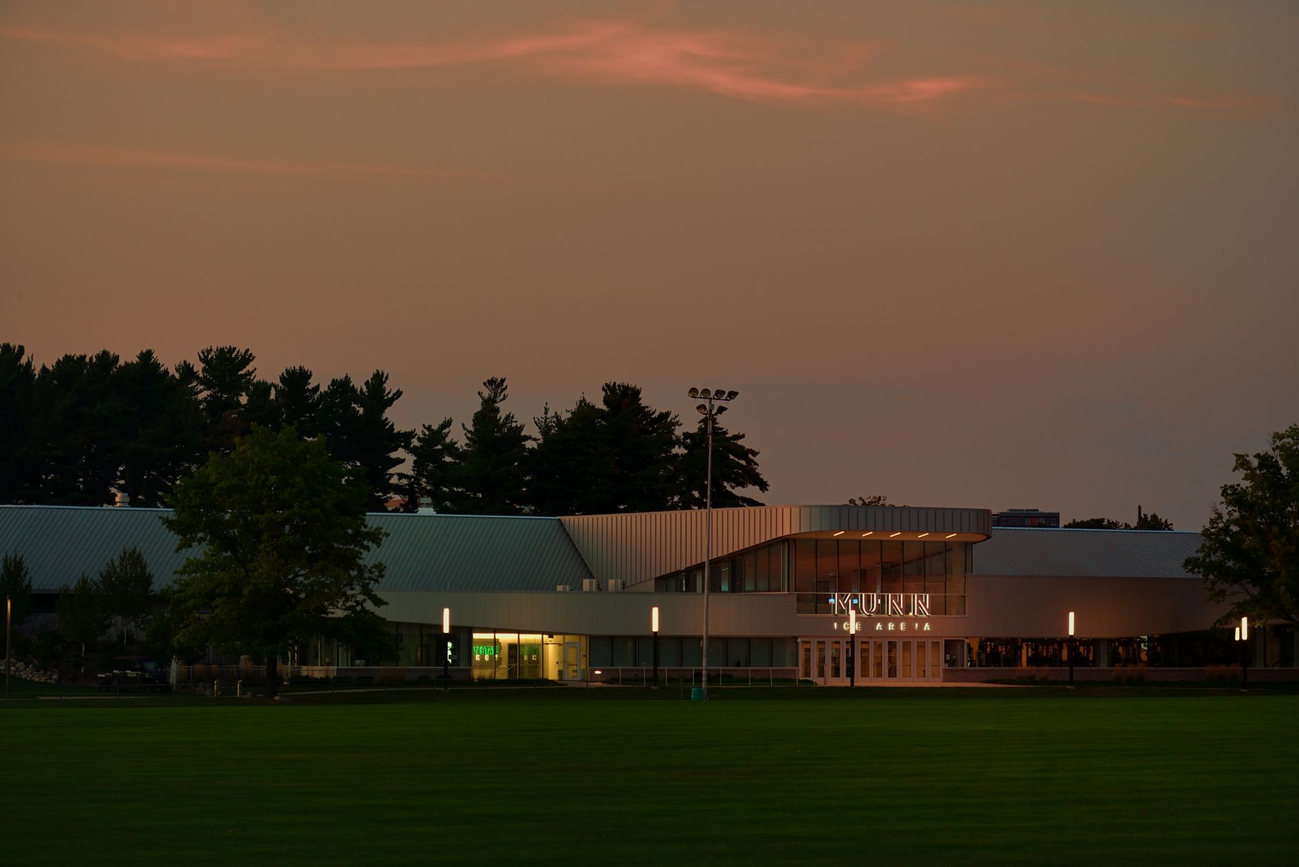 The Kunn Ice Arena illuminated in the early evening, set against a moody sky in East Lansing, Michigan.