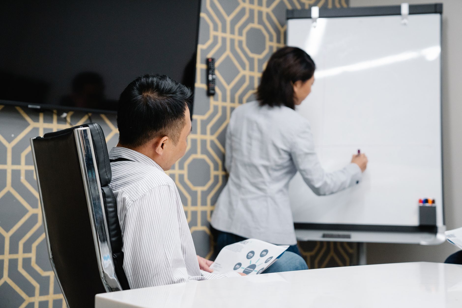 Business professionals engaging in a collaborative meeting using a whiteboard for brainstorming.