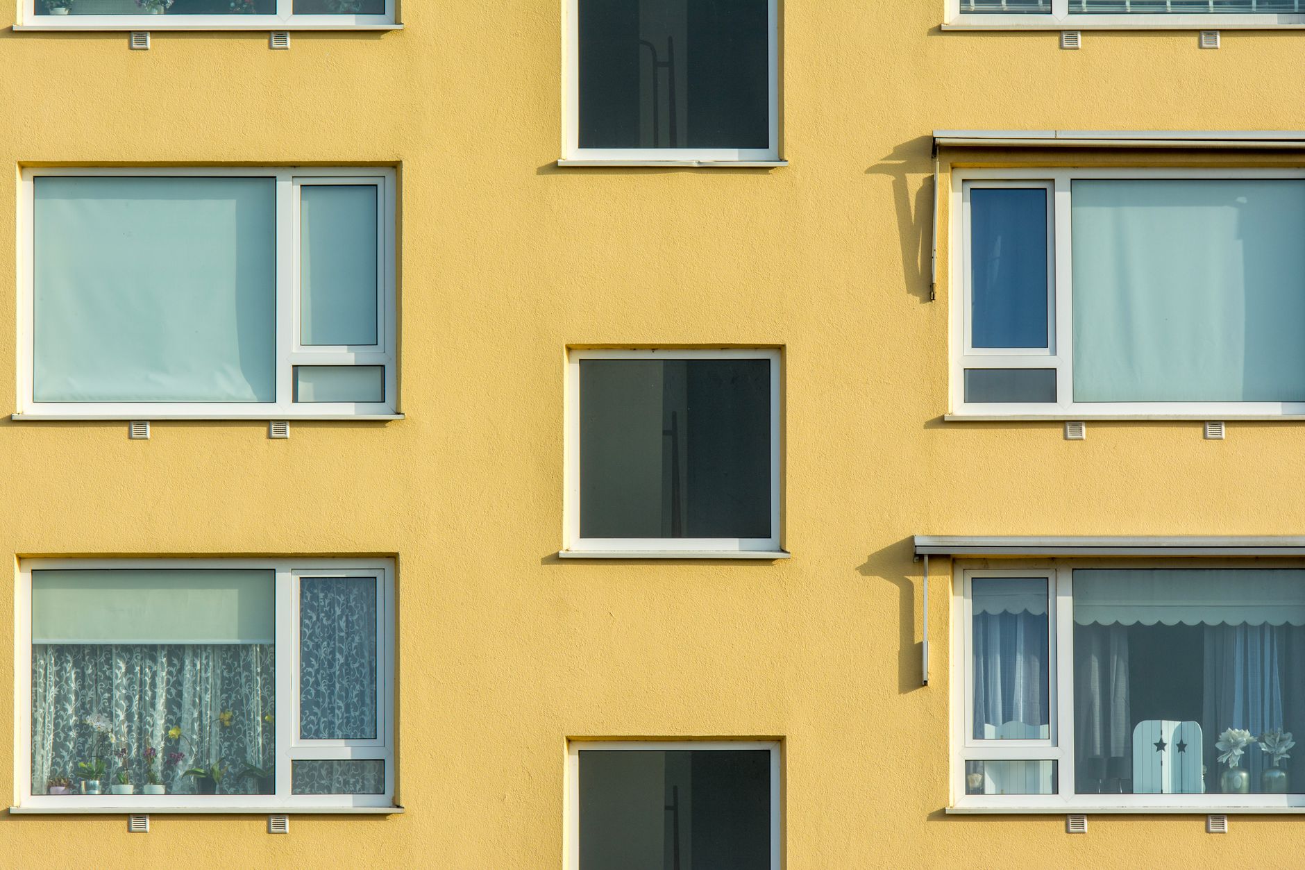Close-up view of a yellow apartment building facade with windows and balconies.