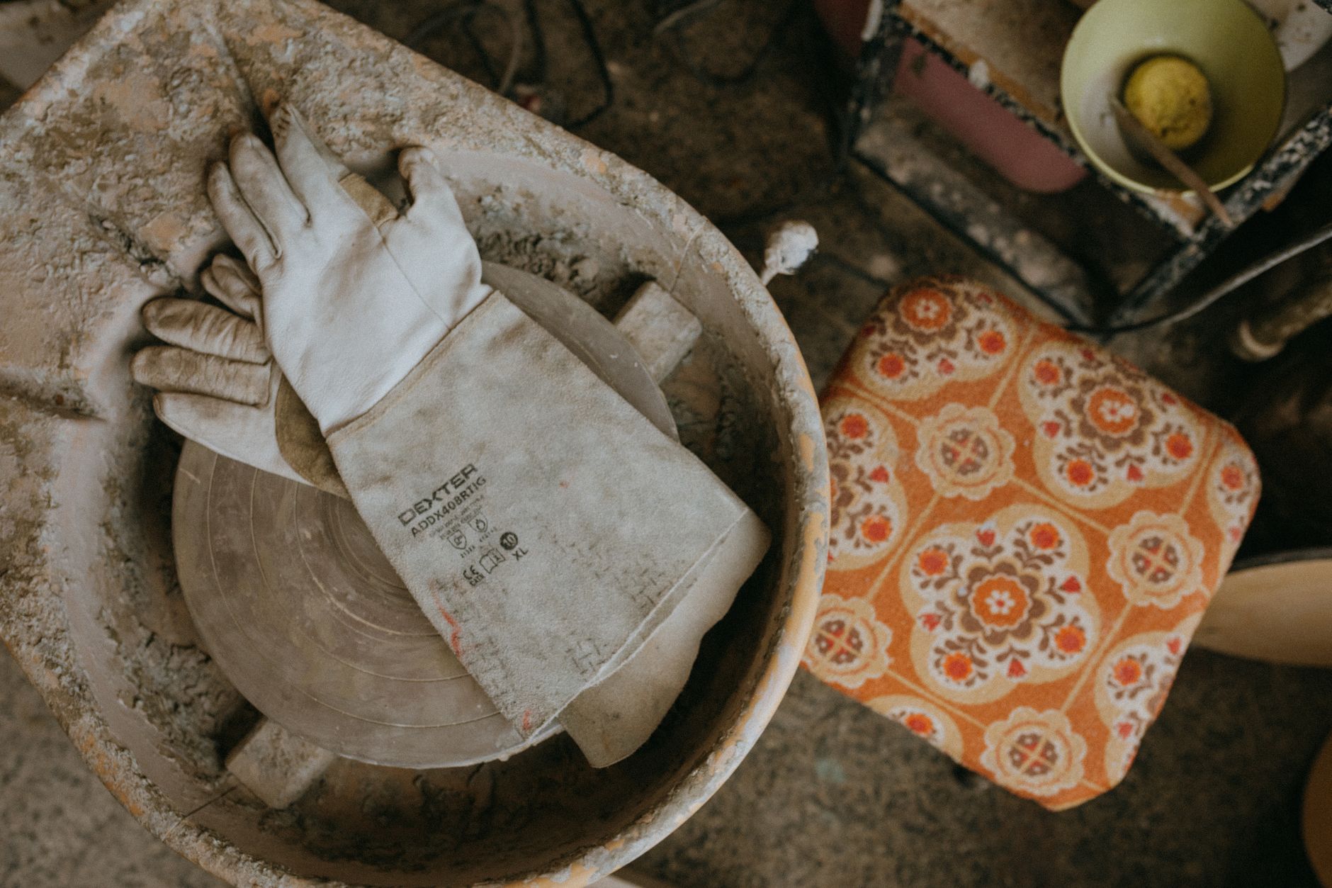 Close-up of a pottery wheel with gloves in a rustic ceramic workshop.