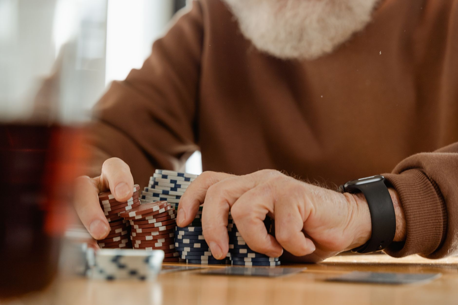 Senior adult focused on playing poker with chips at a table indoors. Captured with a warm, vintage feel.