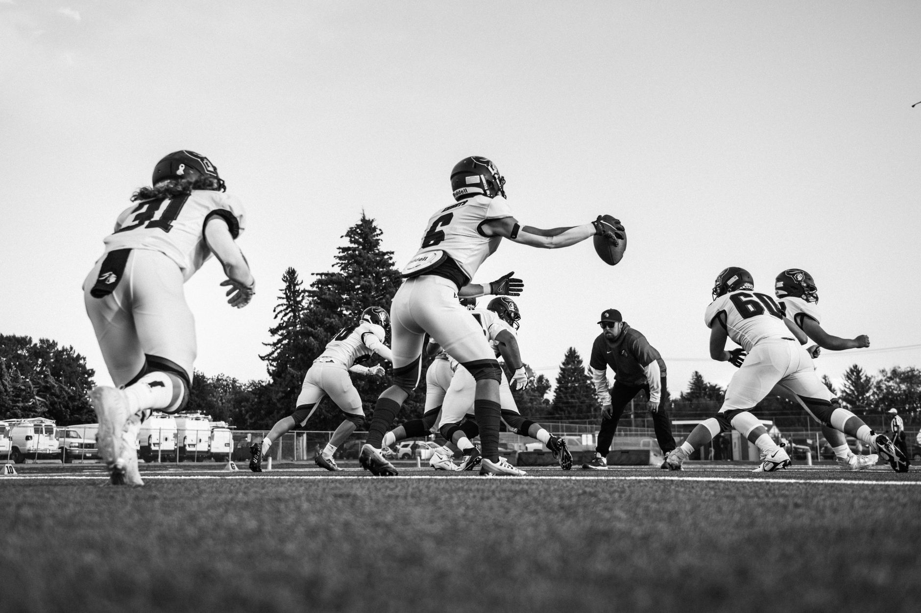 Energetic black and white image of football players practicing, highlighting teamwork and action.