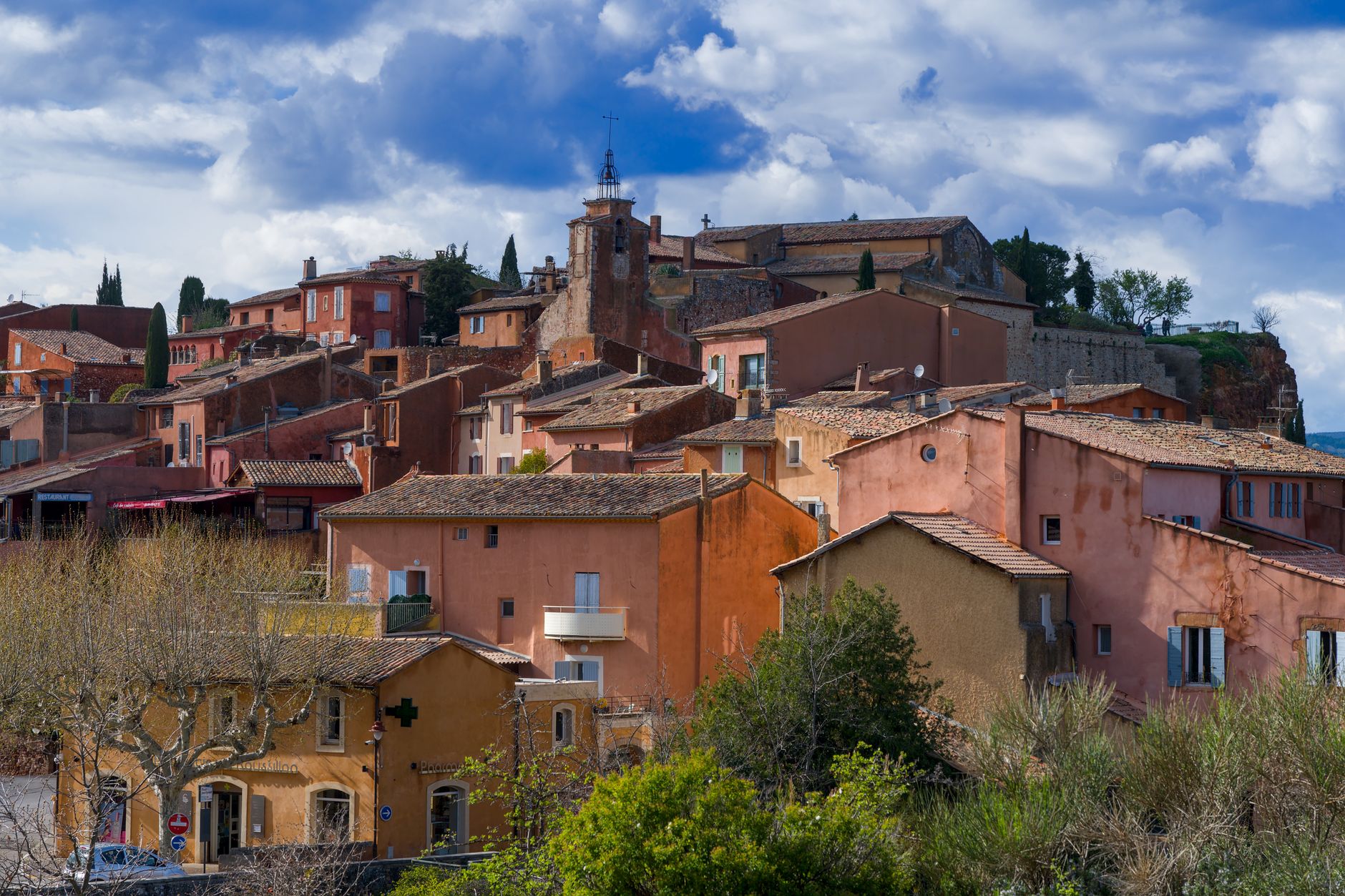 Scenic view of the ochre-colored village of Roussillon, Provence, under a vibrant sky.