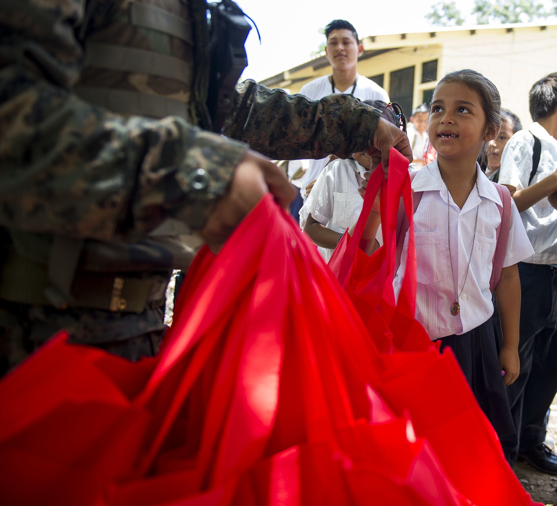 A schoolchild at the Gabriela Mistral School in Ocotes Alto, Honduras, received humanitarian aid from a Honduran Army 15th Battalion soldier July 20, 2015. New Horizons Honduras 2015 training exercise personnel visited the Gabriela Mistral to deliver tote bags, backpacks, books and food as part of the humanitarian aid mission organized by 81st Civil Affairs Battalion civil affairs Soldiers out of Fort Hood, Texas. New Horizons was launched in the 1980s and is an annual joint humanitarian assista