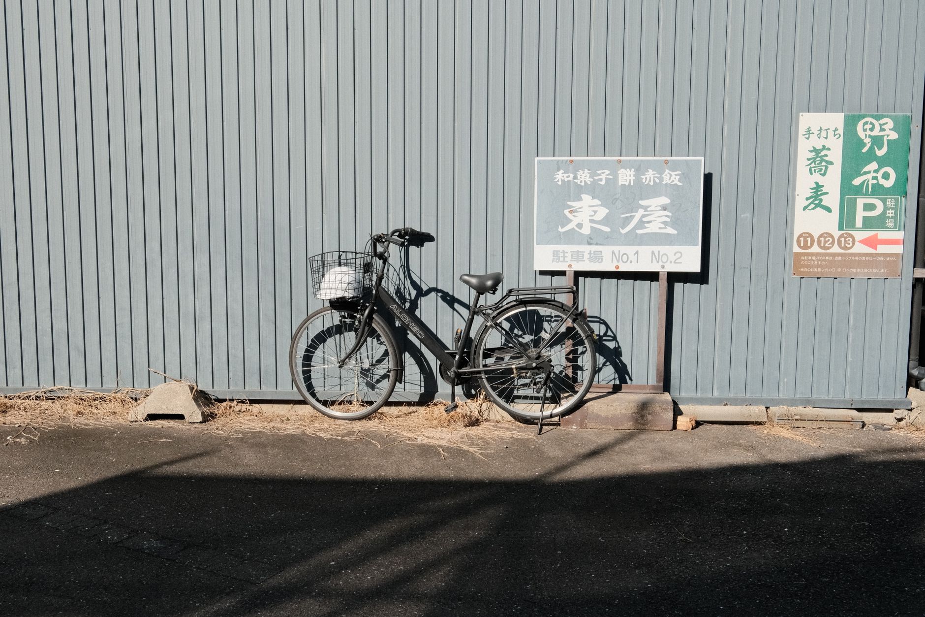 A classic bicycle rests against a textured wall in Inuyama, Japan, capturing a serene urban moment.
