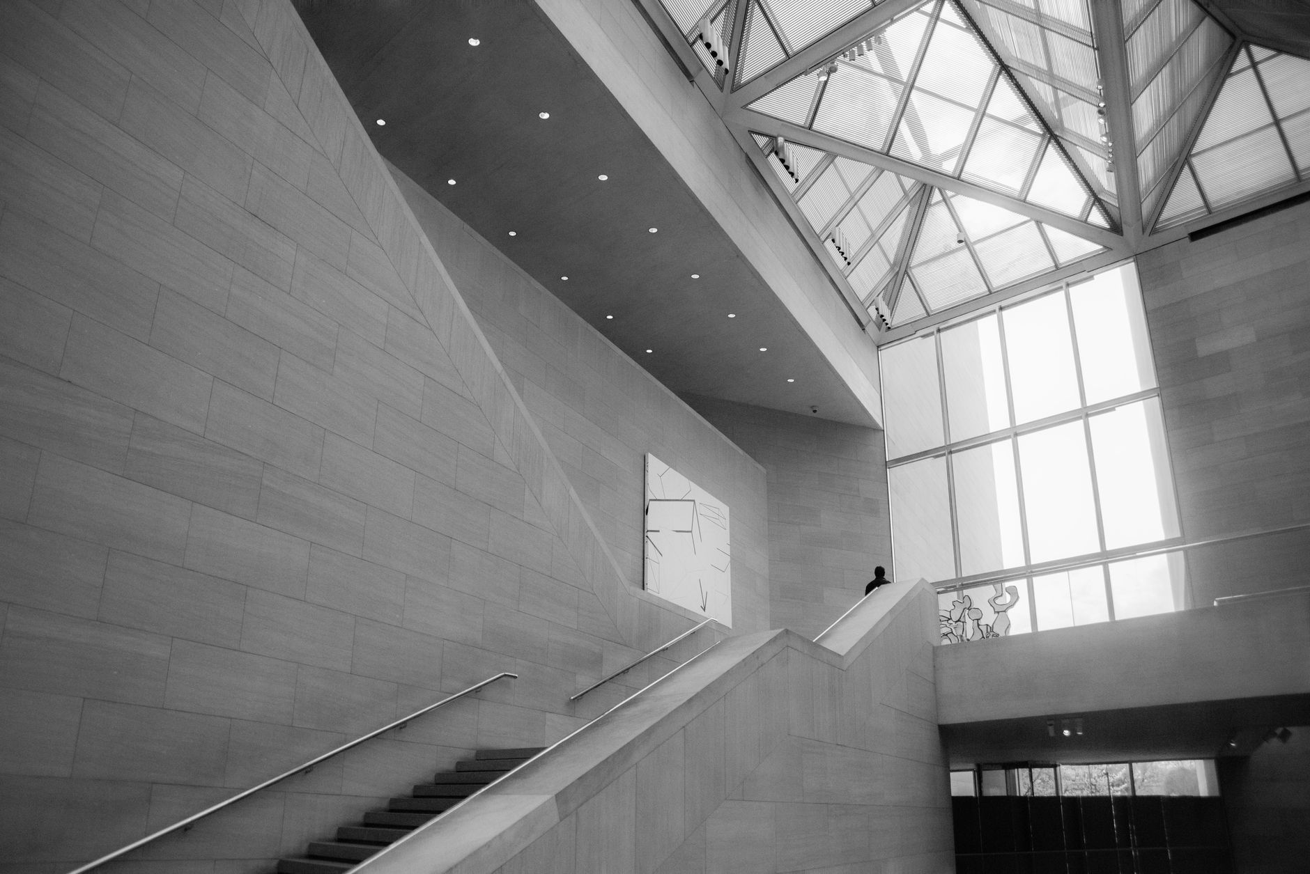 Monochrome interior shot of modern architecture with minimalistic design, glass skylight, and ascending staircase.