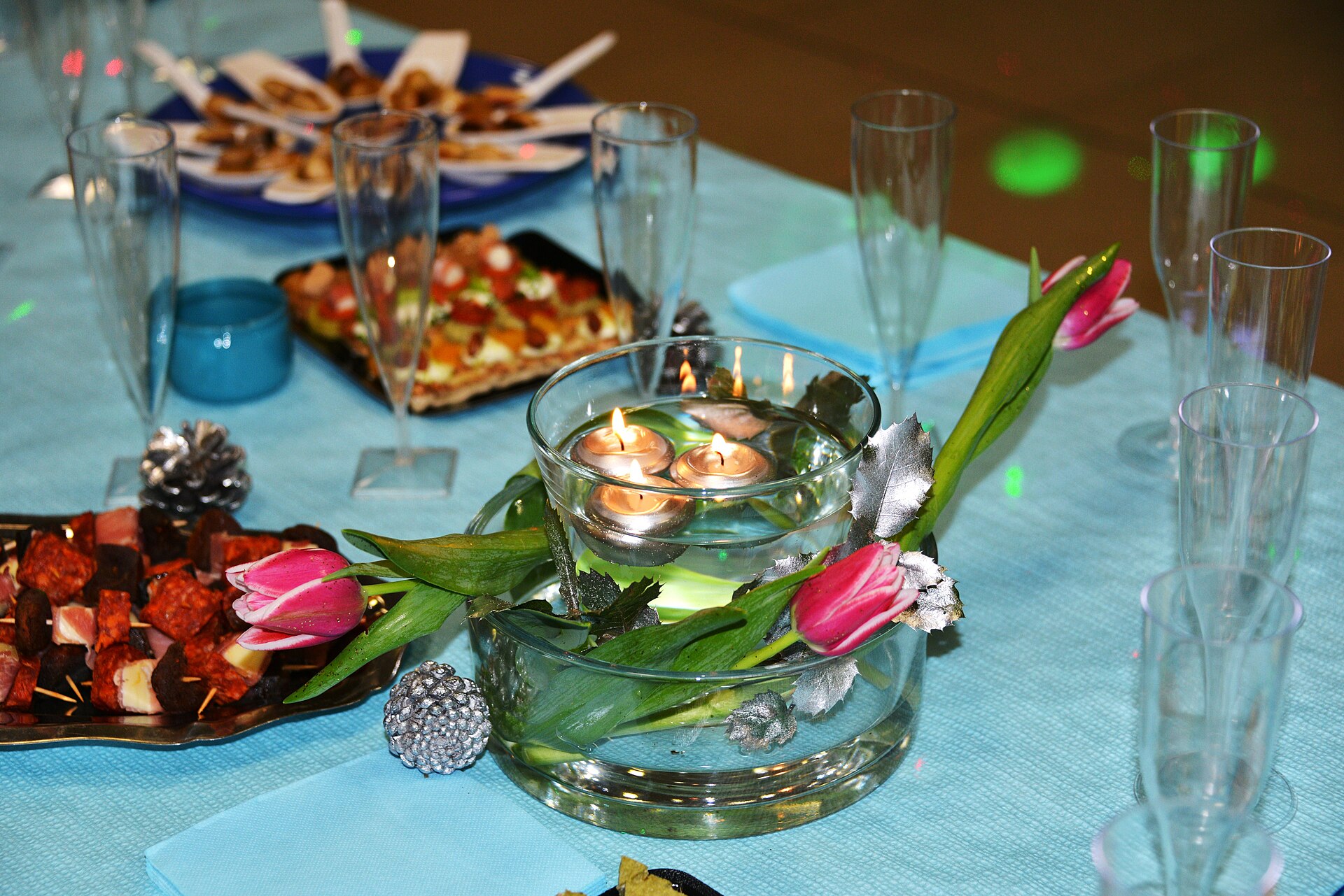 Un photophore en verre avec eau et fleurs pour agrémenter une table à apéritif ou en faire une décoration de centre de table. Réalisation: une coupe circulaire avec de eau et des fleurs dans laquelle on met un vase avec de l'eau et des bougies flottantes. Photographie prise lors d’un réveillon, le 31 décembre 2014 à La Rochelle (France).