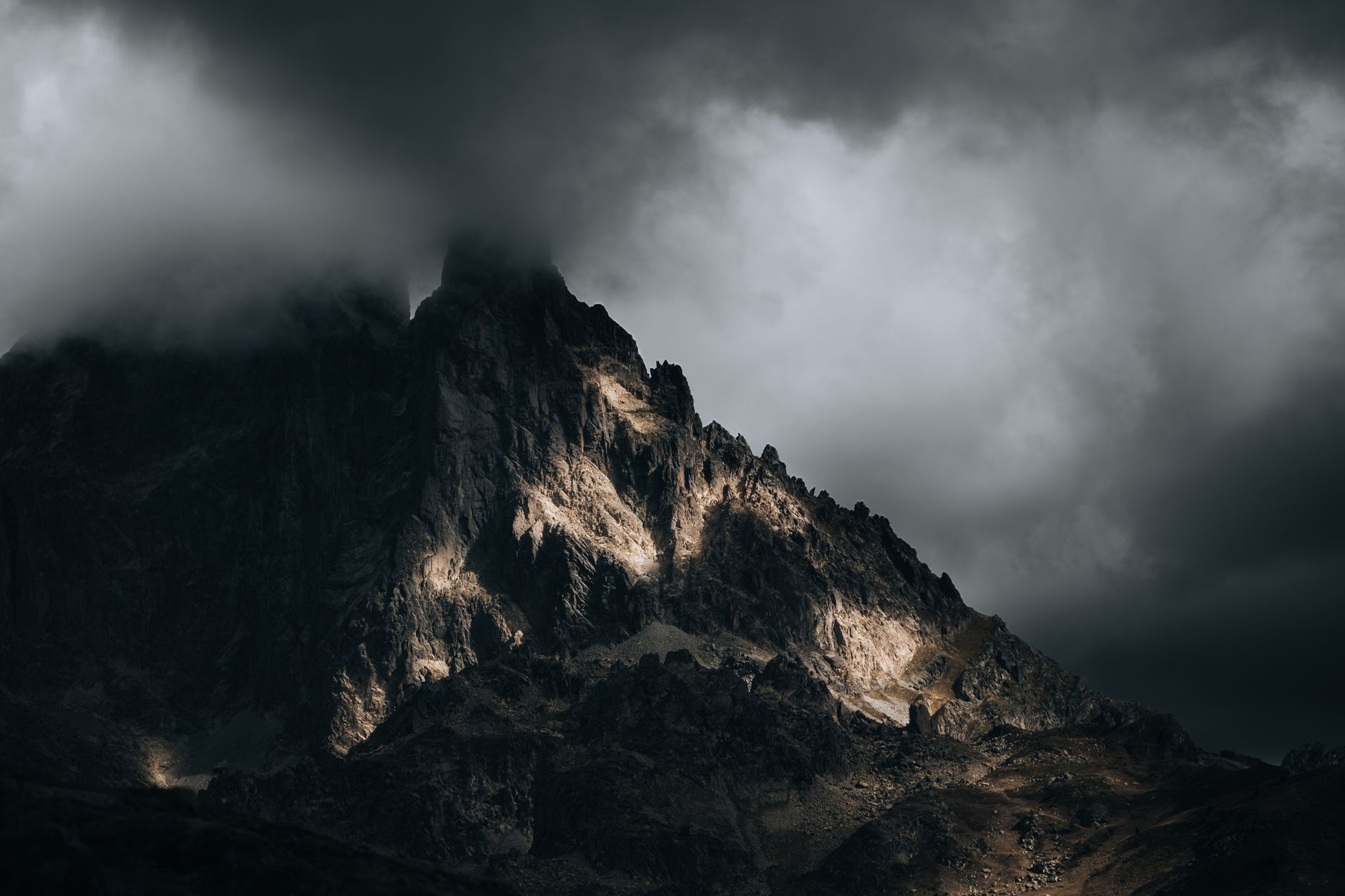 Dark clouds envelop a rugged mountain peak creating a dramatic landscape scene.