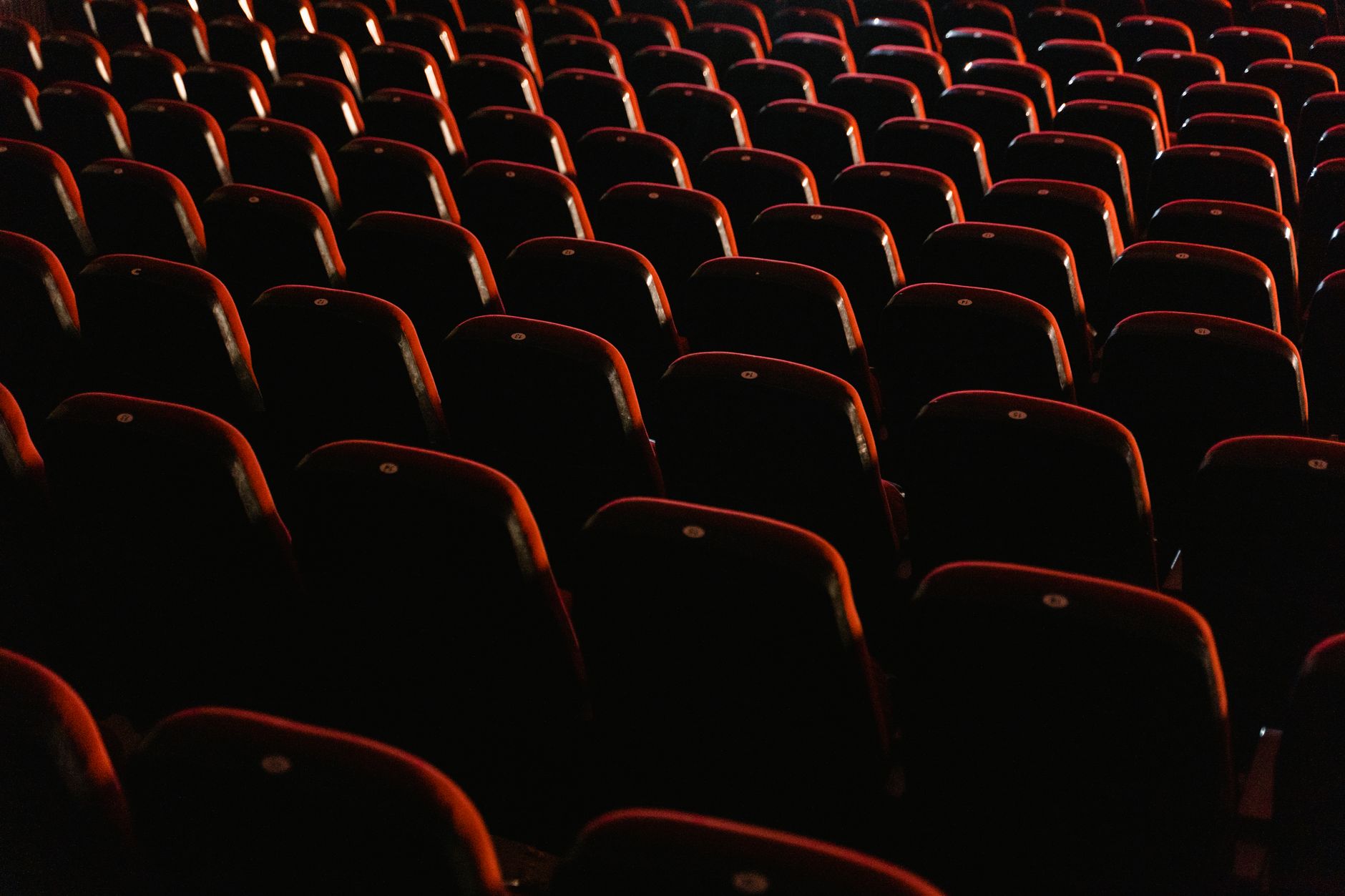 A view of empty red theater seats lit softly, showcasing the quiet ambiance of a cinema.