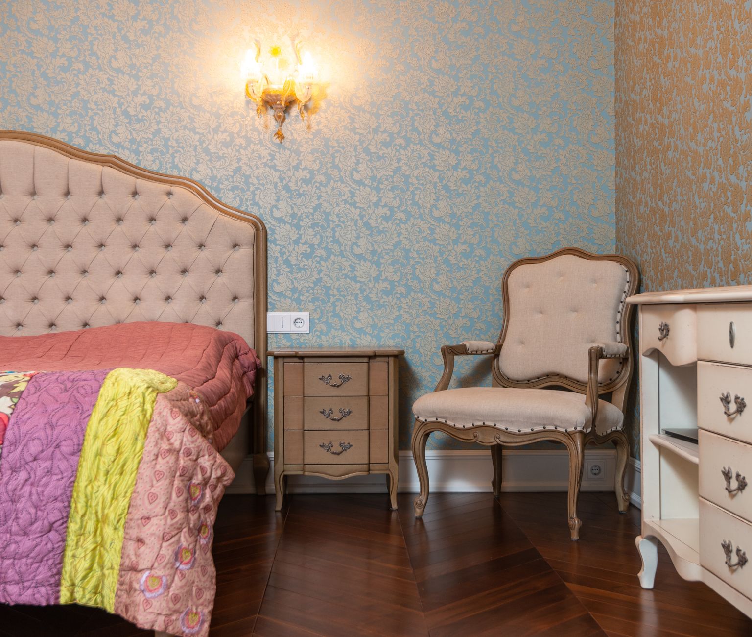 Chic bedroom decor featuring vintage furniture, patterned wallpaper, and cozy lighting.