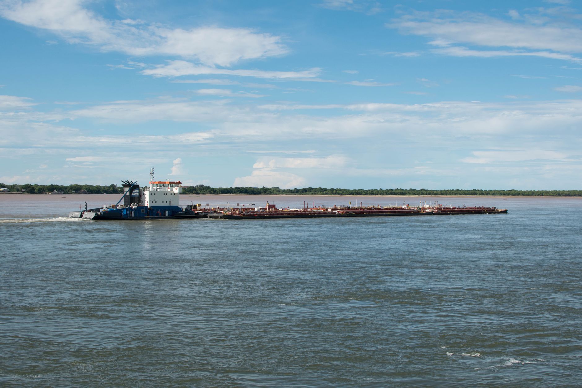 A cargo barge navigates the Parana River under a clear blue sky in Corrientes, Argentina.