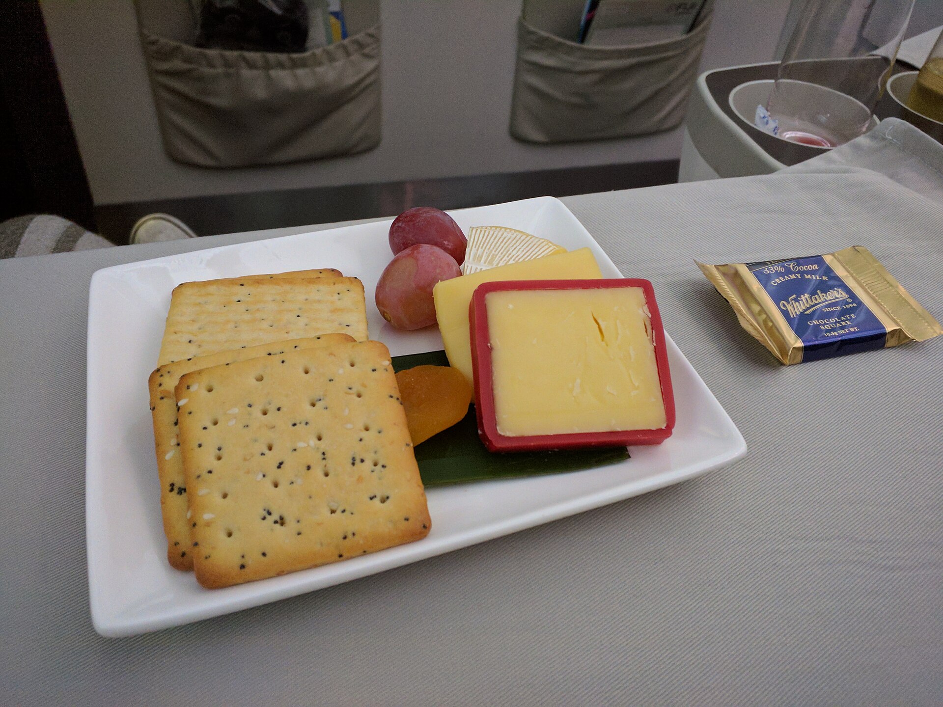 Cheese course of a business class meal on Fiji Airways flight 910 from Sydney to Nadi, consisting of Camembert, cheddar and Edam, along with red grapes, dried apricots, crackers and chocolate.