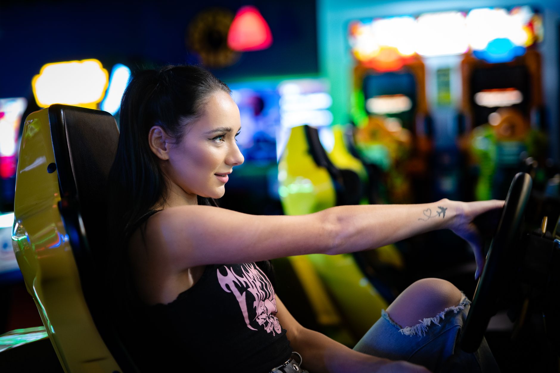 A young woman immersed in playing an arcade racing game in a vibrant retro arcade setting.
